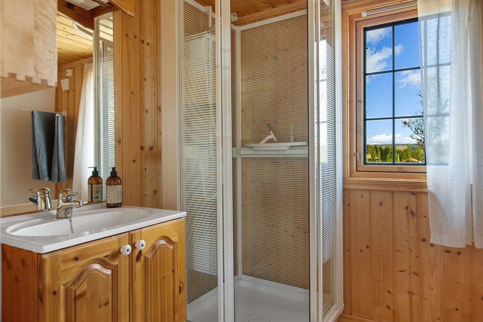 På bad og toalettrom er det heltre gulv, mens vegger og himling er kledd med trepanel. På badet er det servantskap i heltre med profilerte fronter, speil og belysning, samt frittstående dusjkabinett Galleribilde