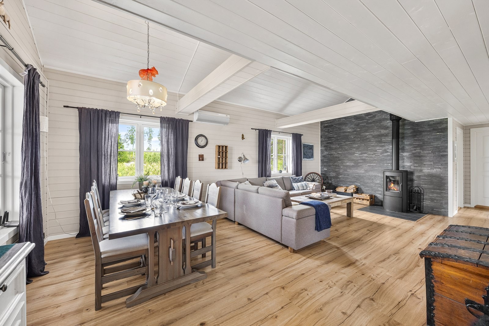 Stuen har laminatgulv i rustikk design, lysmalte vegger i liggende panel og hvitmalt panelhimling med to innkledte dragere. Galleribilde