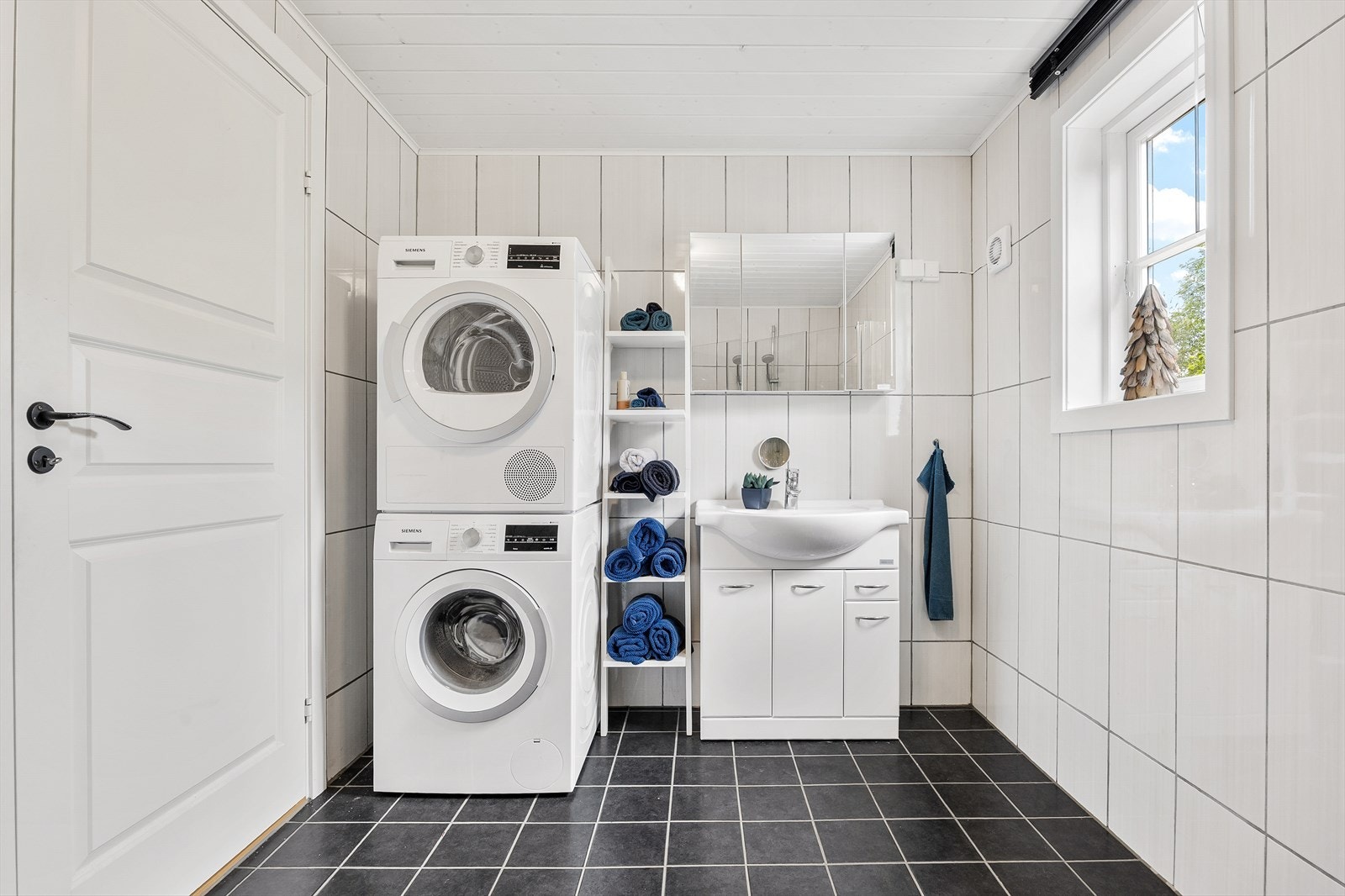 Hovedbadet er innredet med en servant på hvitt servantskap og speilskap. Her er det også opplegg for vaskemaskin og tørketrommel i søyleløsning. Galleribilde