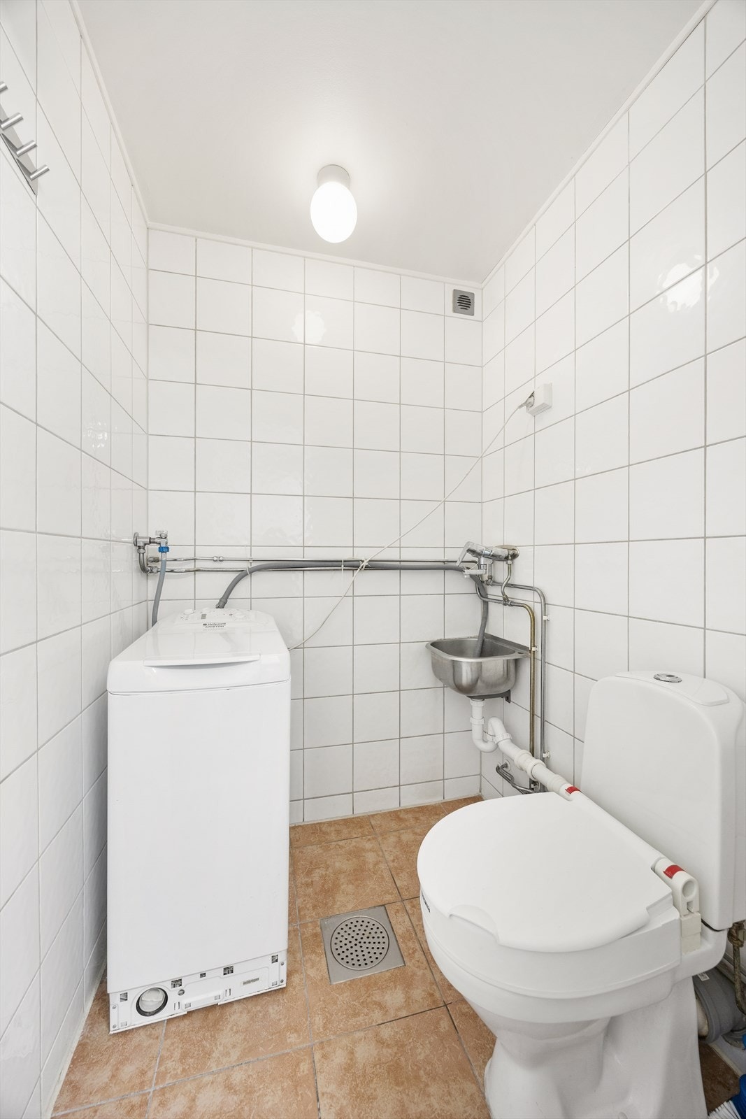Eget vaskerom med fliser på gulv og vegger, samt opplegg for vaskemaskin. Galleribilde