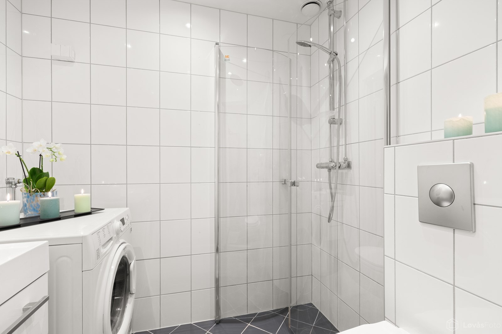 Her finner du flislagte overflater, vegghengt toalett, servant med innredning, dusjhjørne med innfellbare glassdører samt opplegg for vaskemaskin. Galleribilde