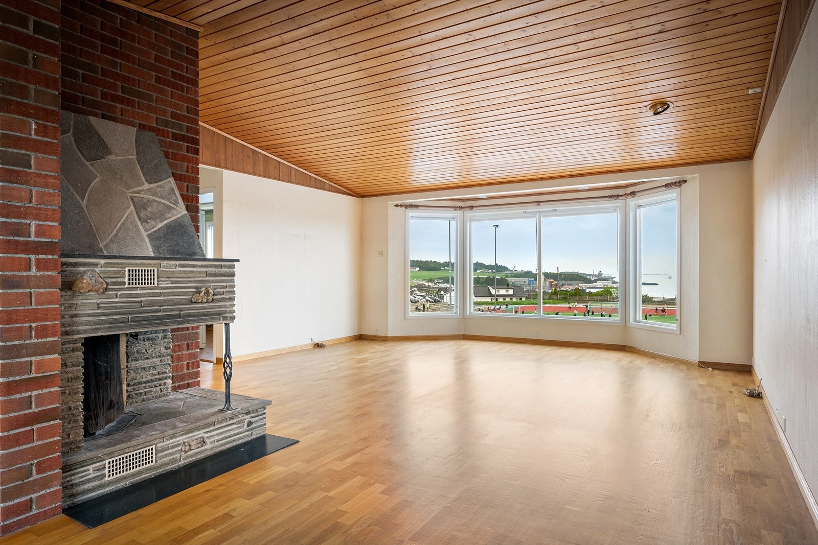 Peisen med gnistfanger og steinplate på gulvet er et sentralt element i rommet. Galleribilde