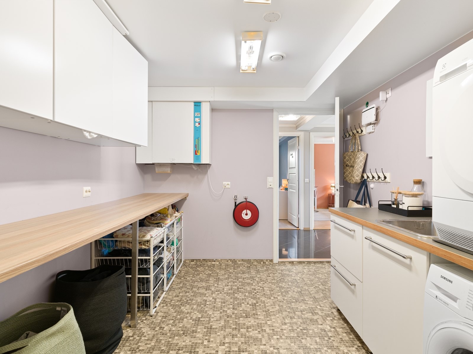 Praktisk og romslig vaskerom med vinylbelegg på gulv, opplegg for vaskemaskin og god benkeplass. Galleribilde