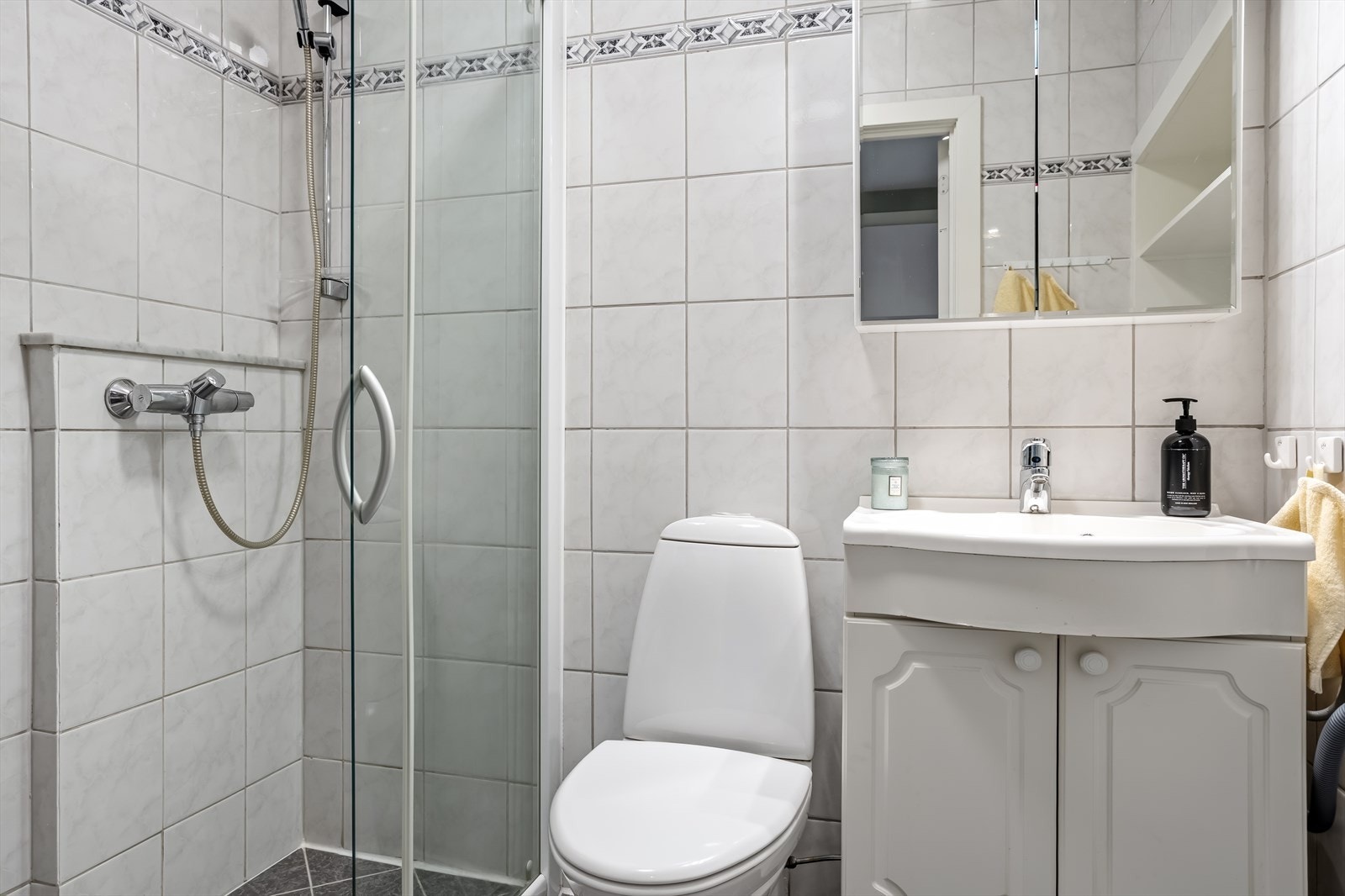 Badet er utstyrt med dusjhjørne, servant med underskap og toalett. Galleribilde