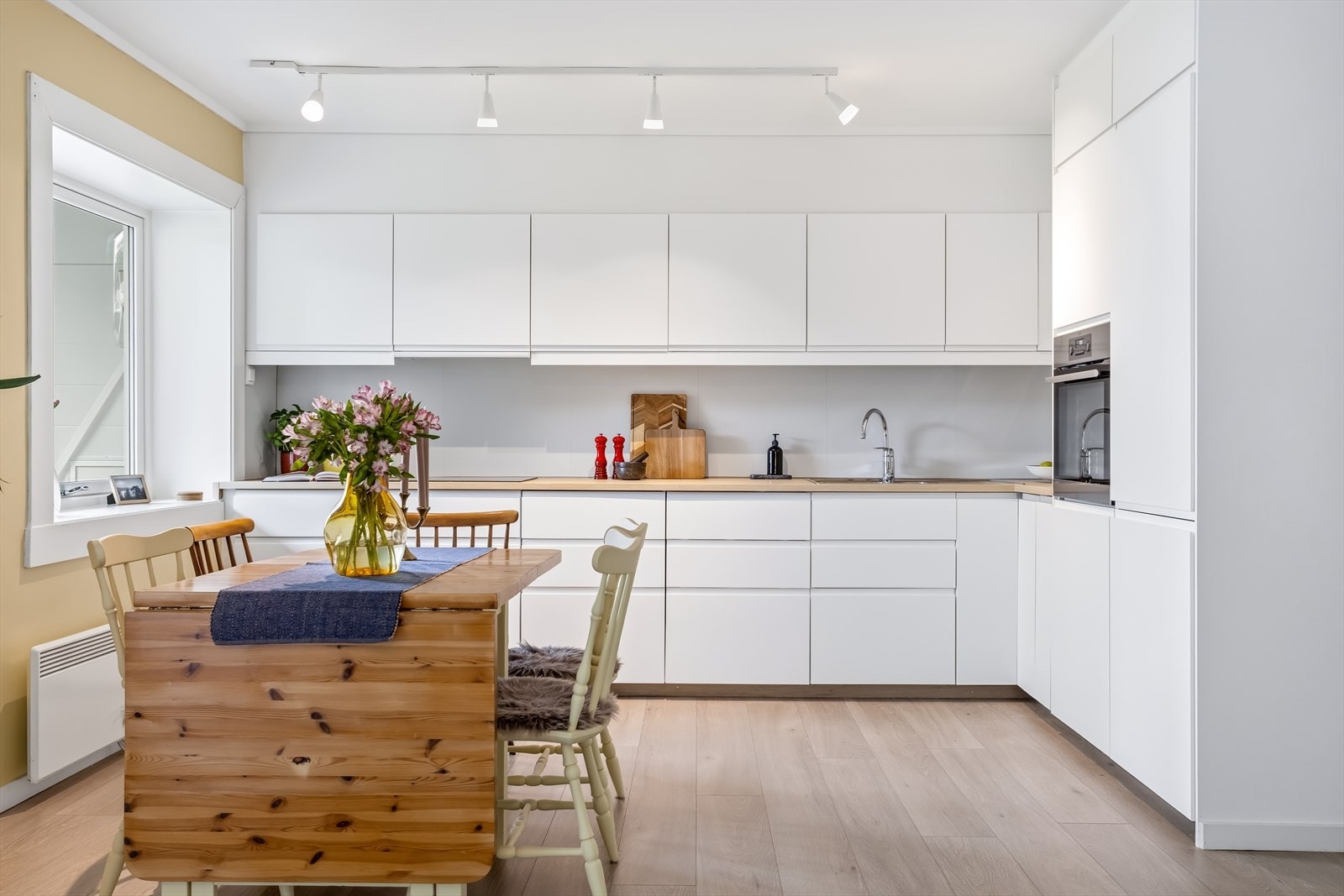 Kjøkkenet har en moderne hvit IKEA innredning med glatte fronter og laminat benkeplate. Galleribilde