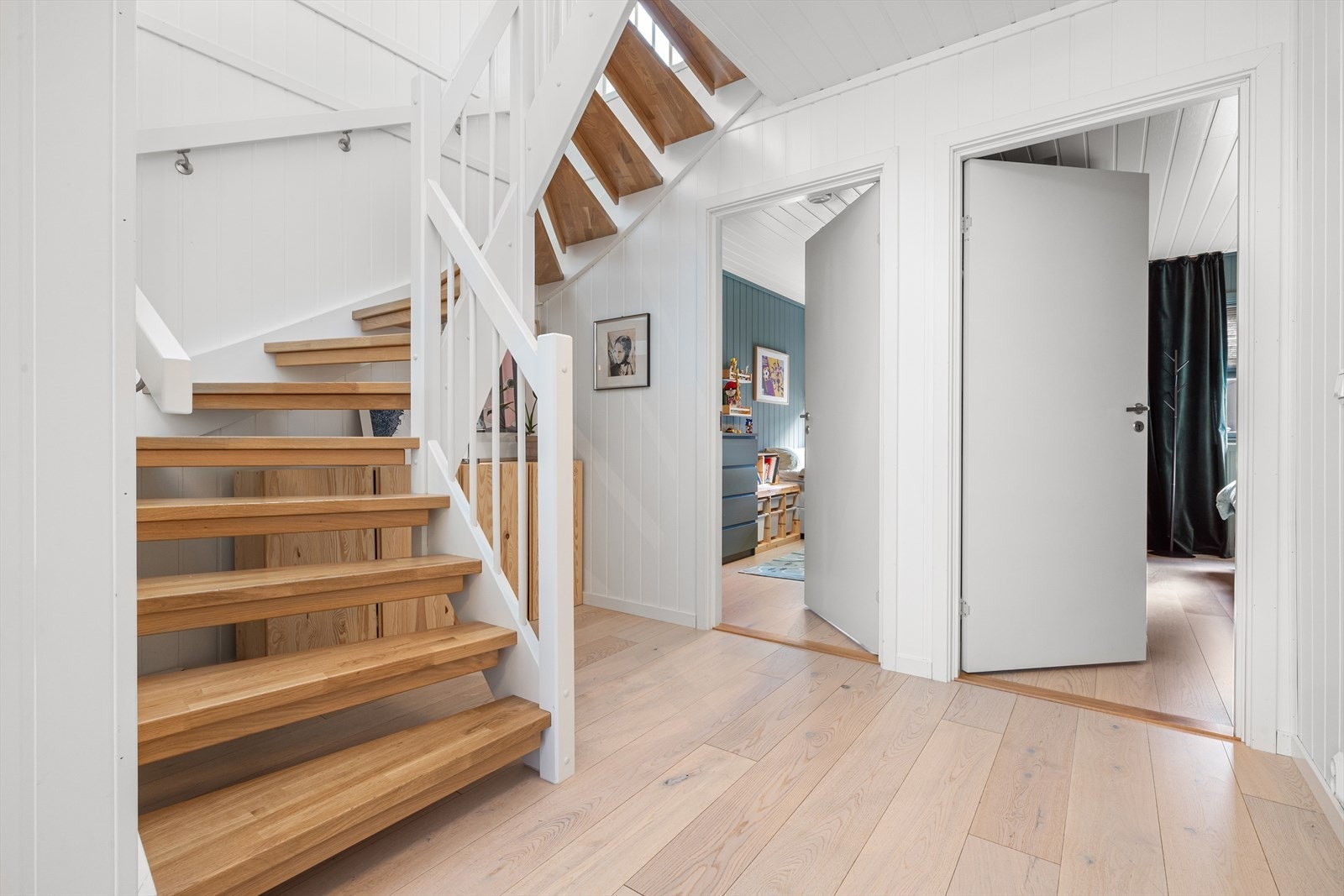 Hallen i første etasje fungerer som et naturlig bindeledd mellom boligens rom, og gir adkomst til boligens 3 soverom, TV-stue og baderom. Herfra går trappen opp til hovedetasjen, som på en stilren måte knytter etasjene sammen. Galleribilde