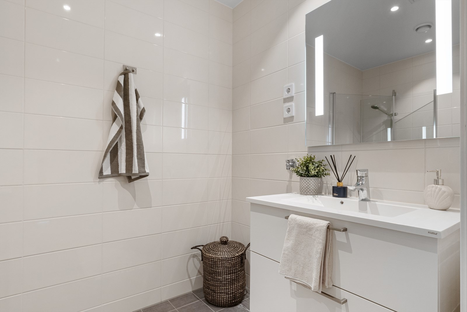 Badet har fliser på gulv og vegger, servantskap og veggmontert toalett med innebygget sisterne. Galleribilde