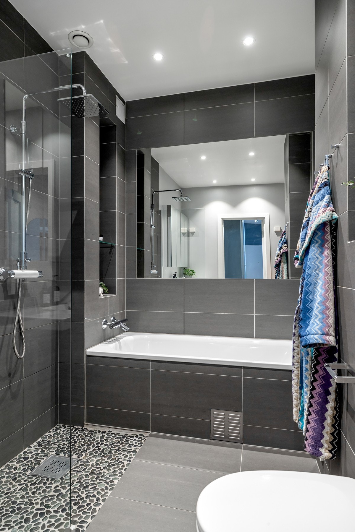 Badet har både regnfallsdusj og et innmurt badekar, hvor den praktiske nisjen i veggen gir plass til oppbevaring av såper og øvrige baderomsartikler Galleribilde