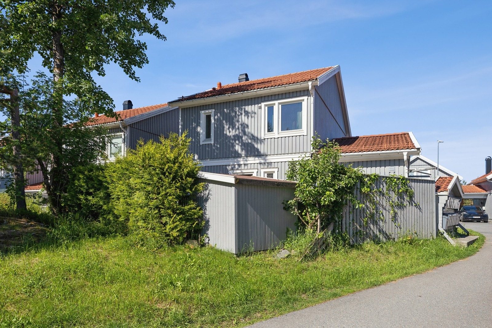 Usjenert terrasse ved fasaden, skjermet av gjerde og klatreplanter - med svært gode solforhold gjennom dagen. Galleribilde