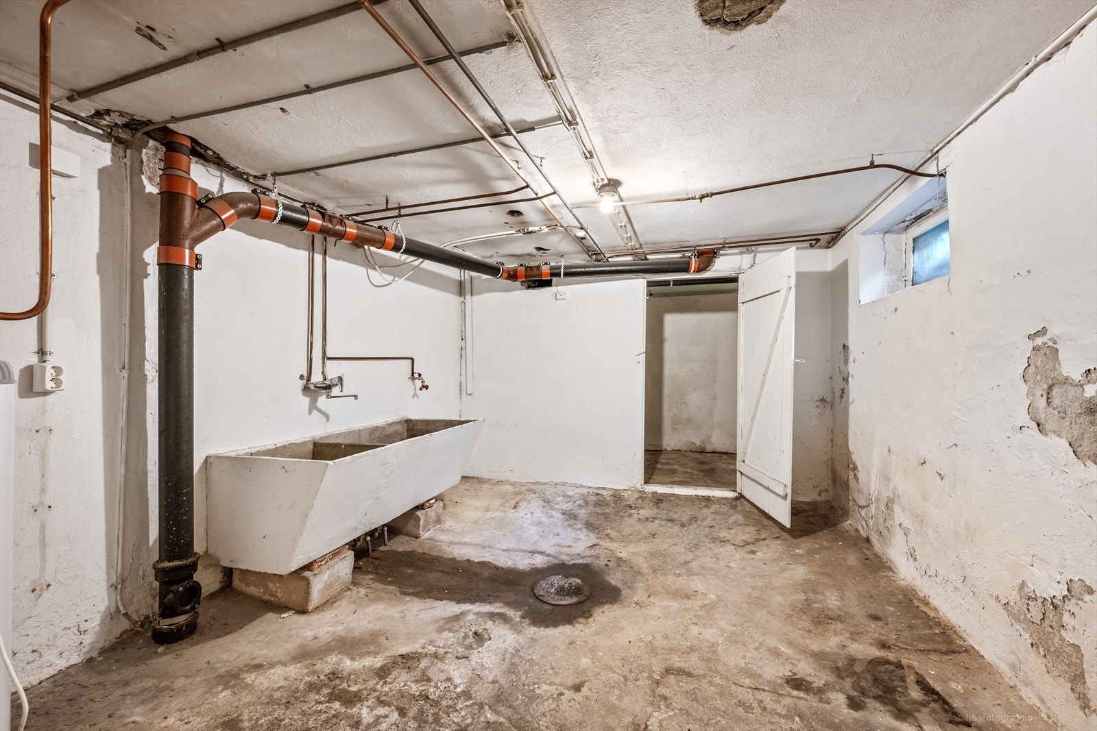 Praktisk vaskerom i kjelleren med betonggulv, støpt skyllekar og opplegg for vaskemaskin. Galleribilde
