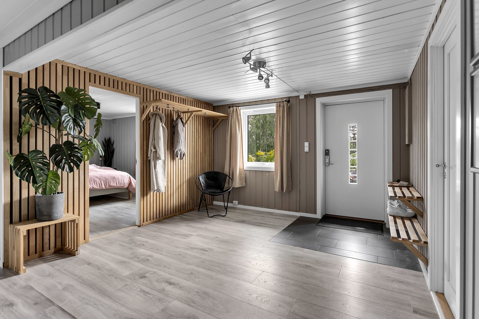 Entréen byr på en romslig planløsning med lekre spilevegger, lyst gulv og praktiske fliser rett innenfor dør. Vinduet sikrer fint dagslys i rommet. Galleribilde
