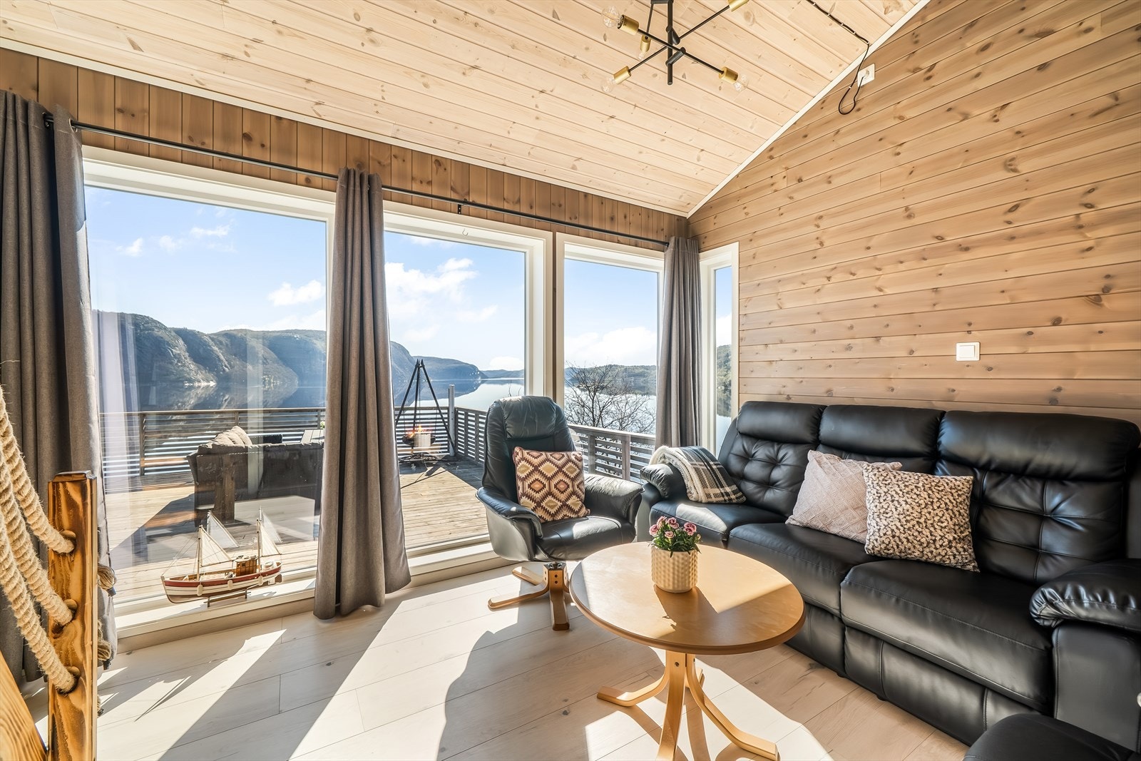 Store vinduer i anneksets stue gir utsikt mot fjorden og utgang til terrassen. Galleribilde