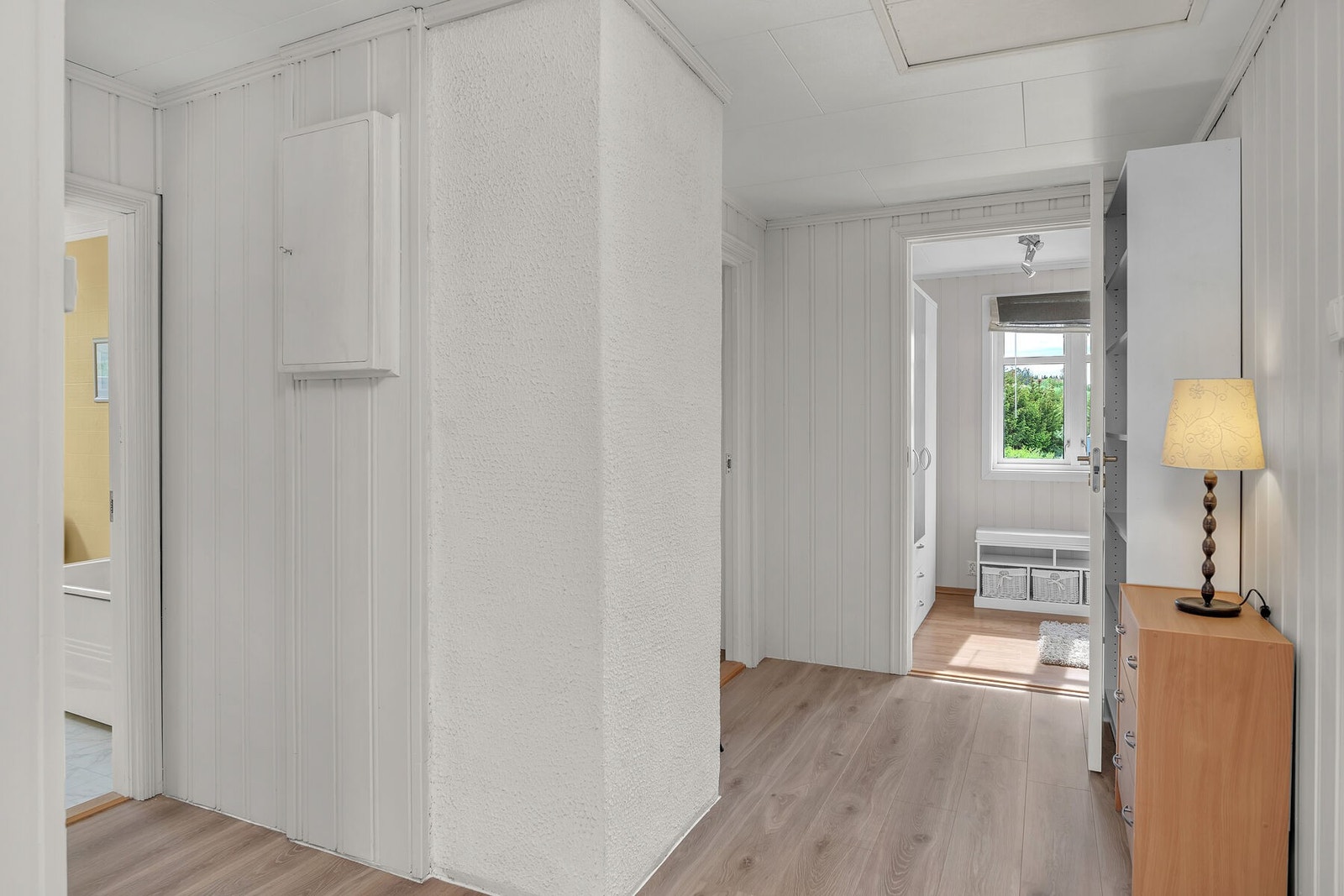 Overflatene i gangen består av laminatgulv og vegger med malt panel. Galleribilde