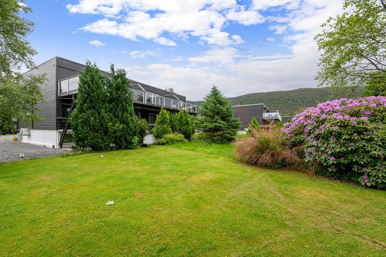 Tomten er opparbeidet med plen, beplantning og terrasseområder. Galleribilde