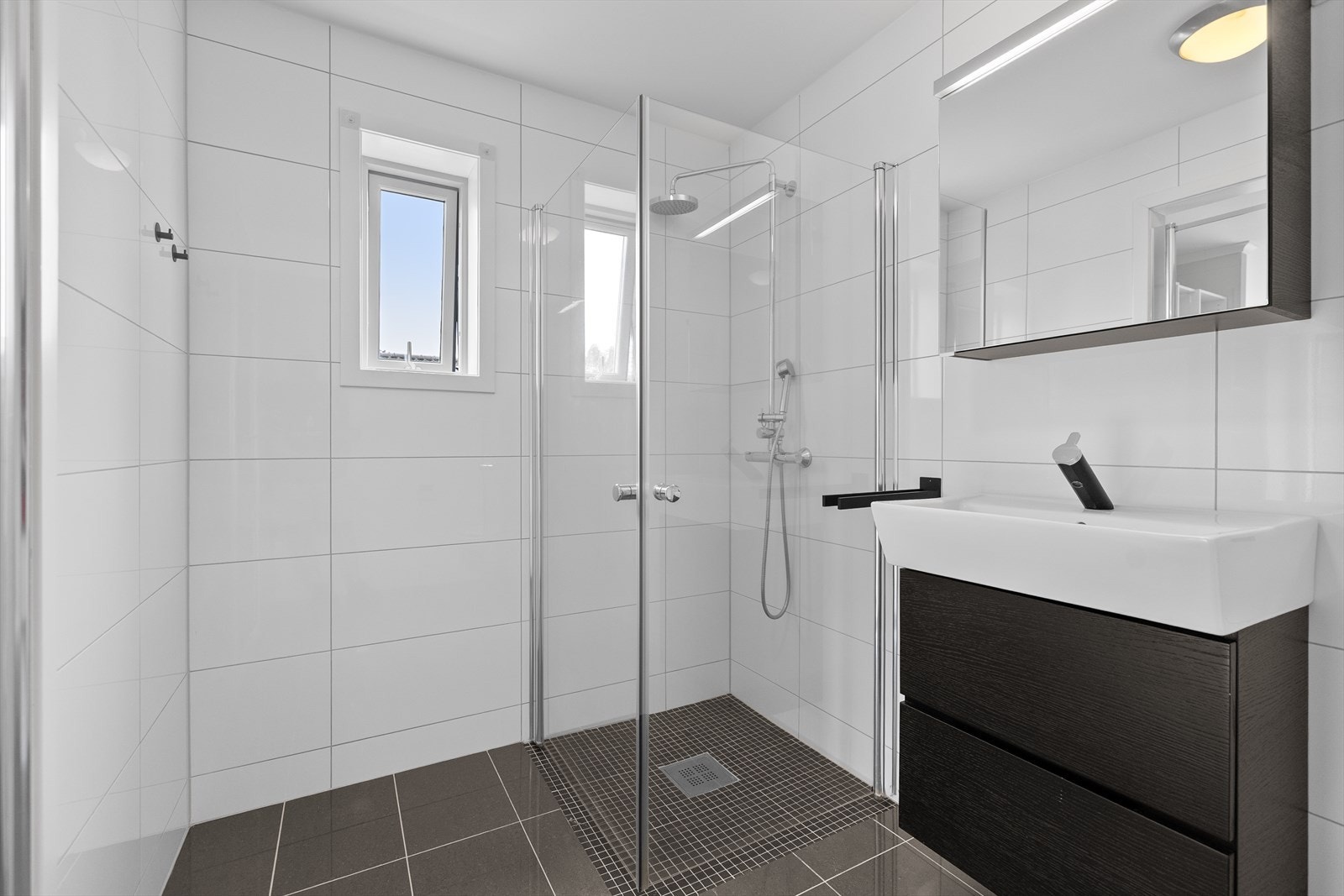Badet fremstår moderne og delikat med flislagte gulv og vegger, kombinert med malte plater i himlingen som gir et lyst og tidløst uttrykk. Gulvvarme sørger for behagelig komfort året rundt og bidrar til en lun atmosfære. Galleribilde