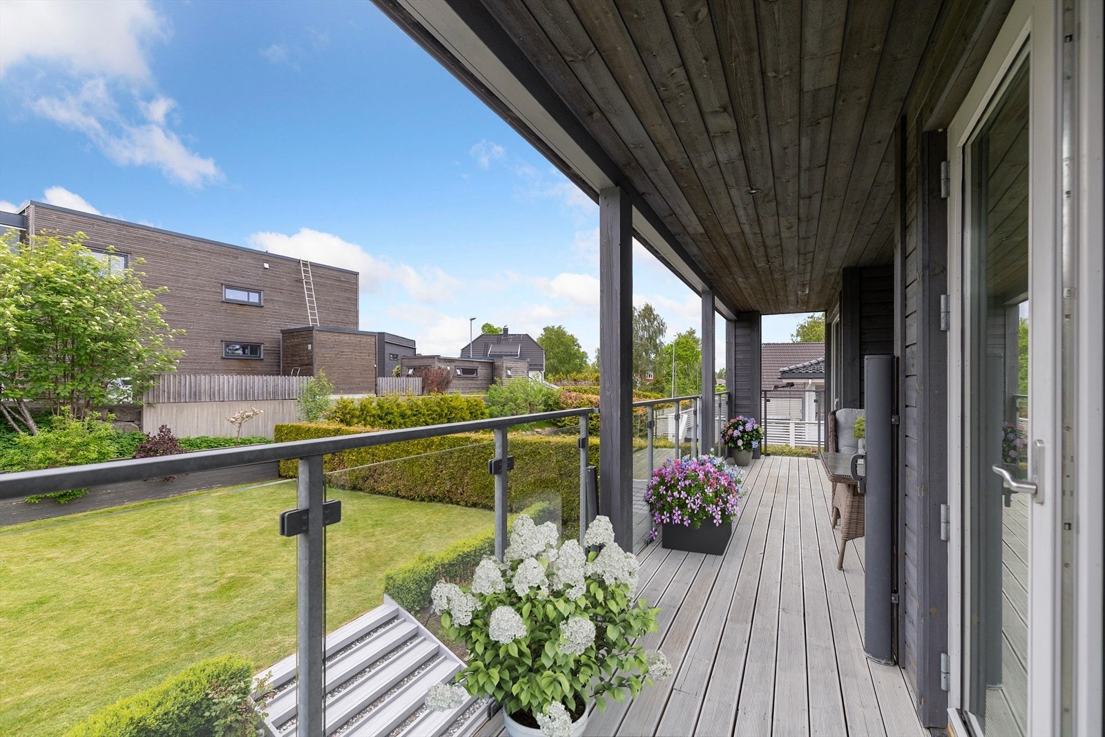 Gulvet er belagt med malte, impregnerte gulvbord, mens rekkverket i glass og galvanisert stål sørger for et moderne uttrykk og bevarer utsynet mot hagen og de grønne omgivelsene nedenfor. Galleribilde
