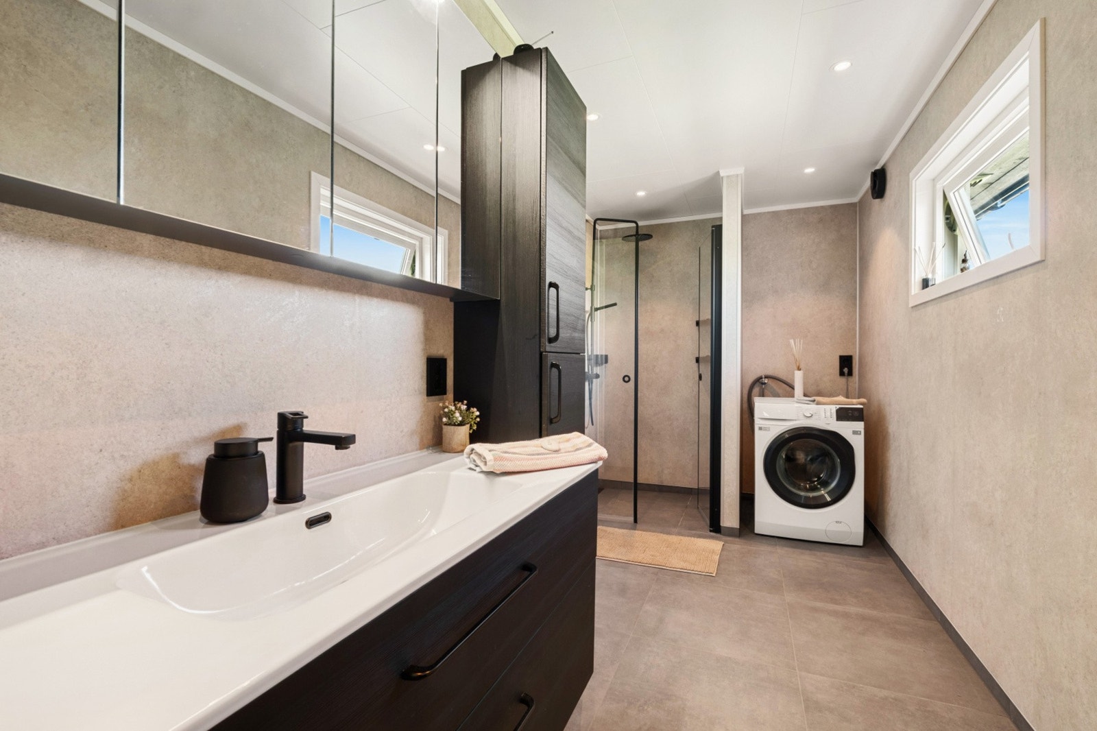 Badet i hovedetasjen er utstyrt med moderne innredning, dusjhjørne og opplegg for vaskemaskin. Galleribilde