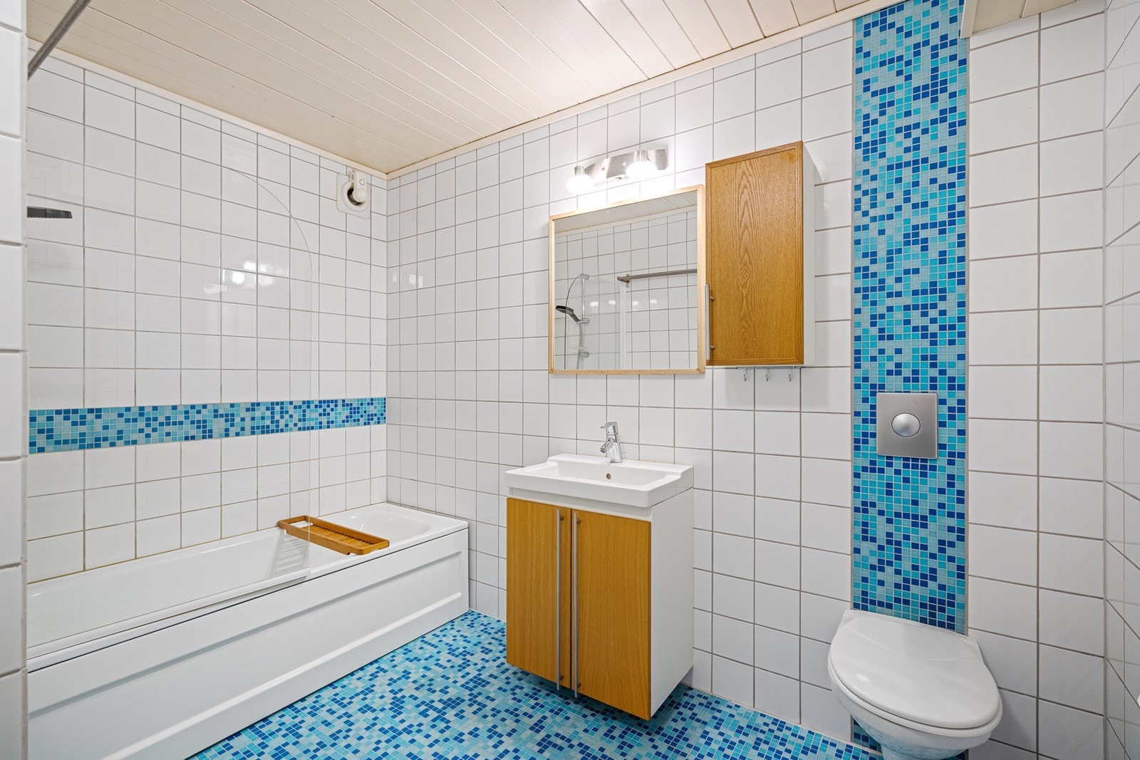Badet i kjelleren er innredet med servant i skapseksjon, badekar og vegghengt toalett. (ikke godkjent) Galleribilde