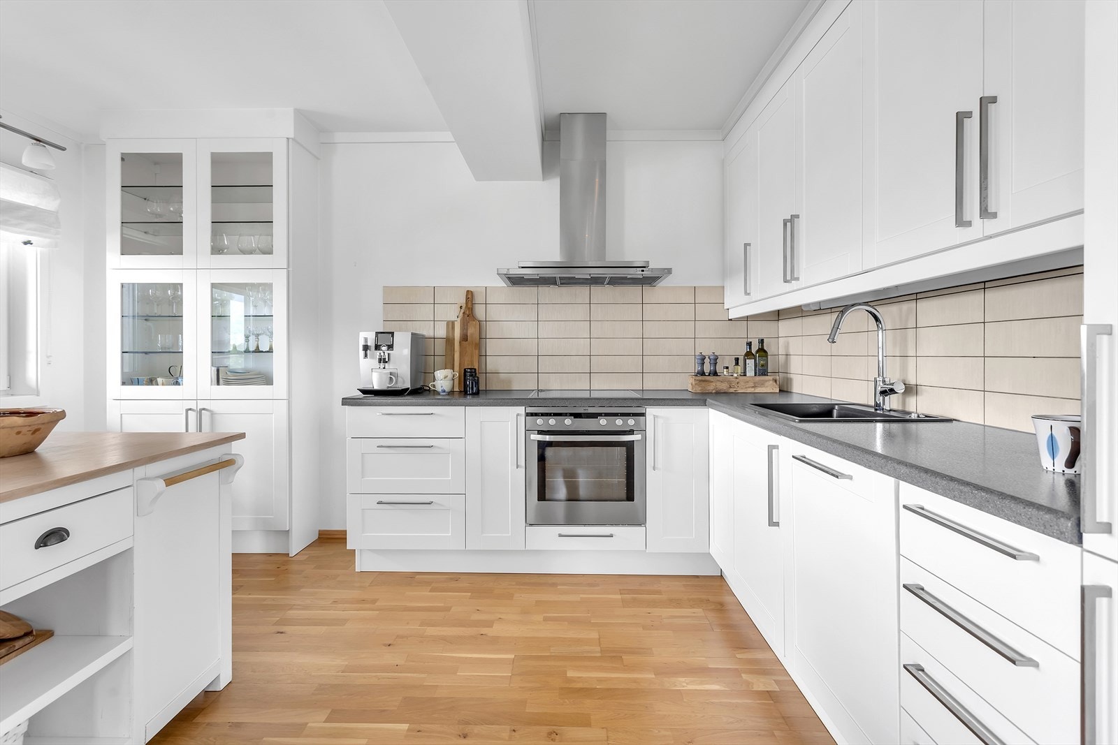 Fliser over kjøkkenbenken gir et elegant uttrykk samtidig som de er enkle å rengjøre.Kjøkkenet er utstyrt med integrerte hvitevarer som inkluderer induksjonstopp, stekeovn, oppvaskmaskin samt kjøleskap (medfølger ikke). Galleribilde