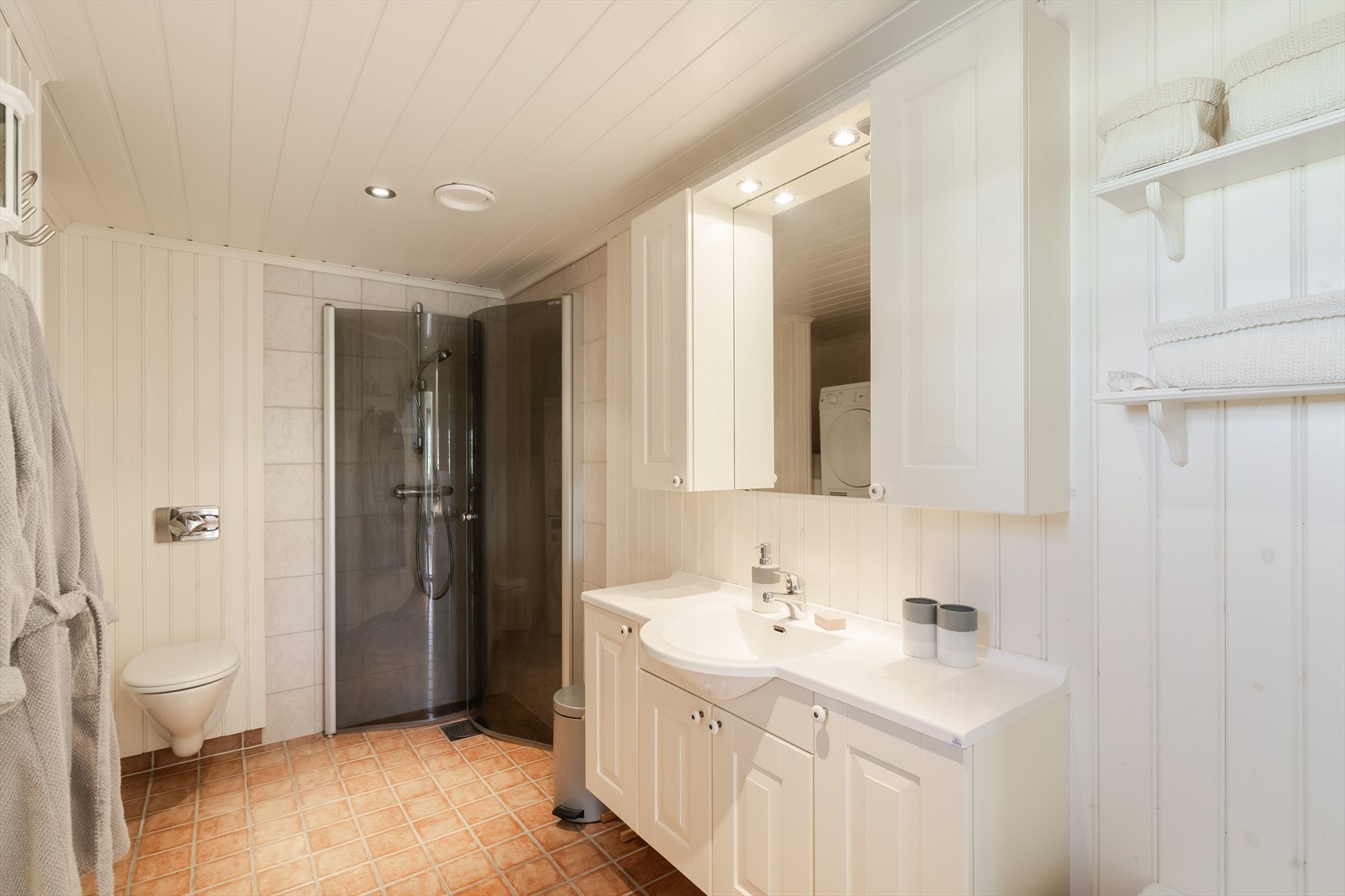 Badet er innredet med nedfelt servant, veggmontert toalett og dusj med innfellbare dusjvegger. Opplegg for vaskemaskin bidrar til en praktisk og funksjonell løsning. Galleribilde
