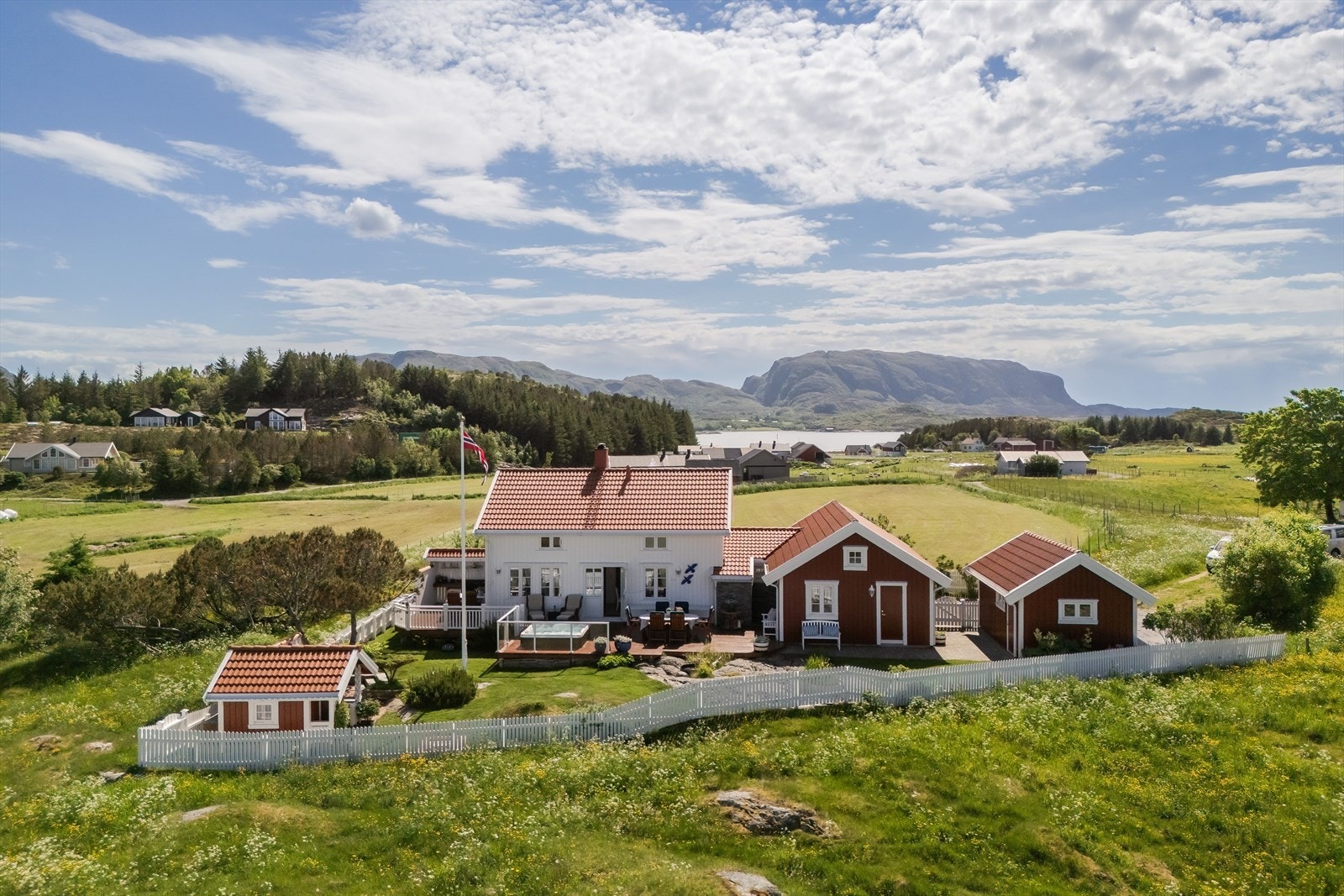 Den sjarmerende hagen er inngjerdet med hvitt stakittgjerde og bidrar til et trivelig uteområde rundt den romslige hovedhytta på 126 m². Galleribilde
