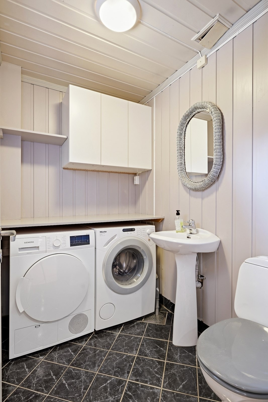 Praktisk vaskerom kombinert med WC, med opplegg for vaskemaskin og tørketrommel. Galleribilde