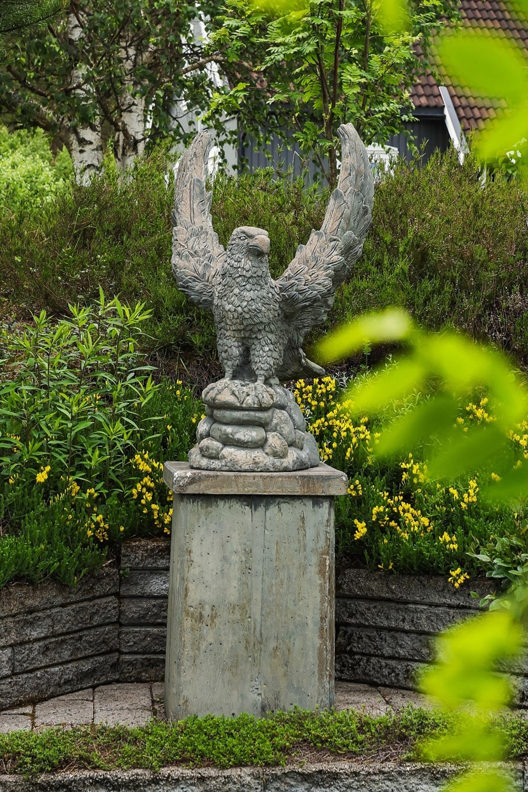 Detalj fra hagen, som er opparbeidet med beplantning, plen og dekorative elementer. Galleribilde