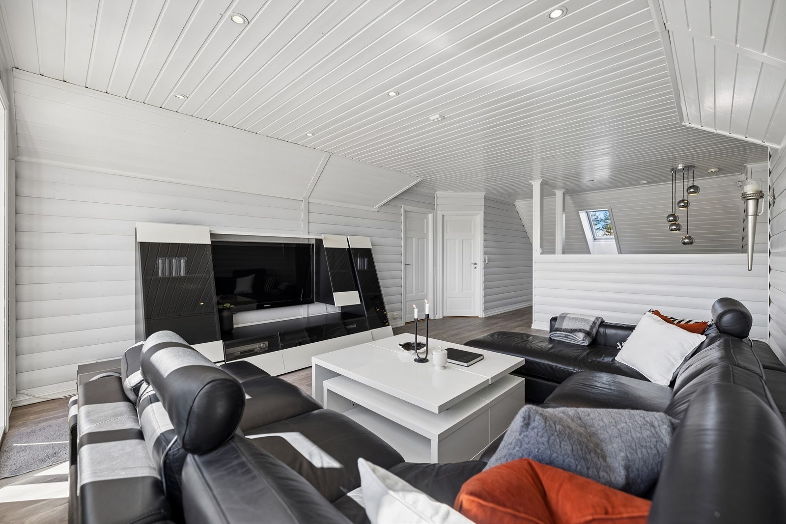 Lys og lun loftstue med skråhimling, paneldetaljer og fleksibel møblerbar flate - fint som TV-stue, ungdomssone eller arbeidsrom, med direkte utgang til balkong. Galleribilde