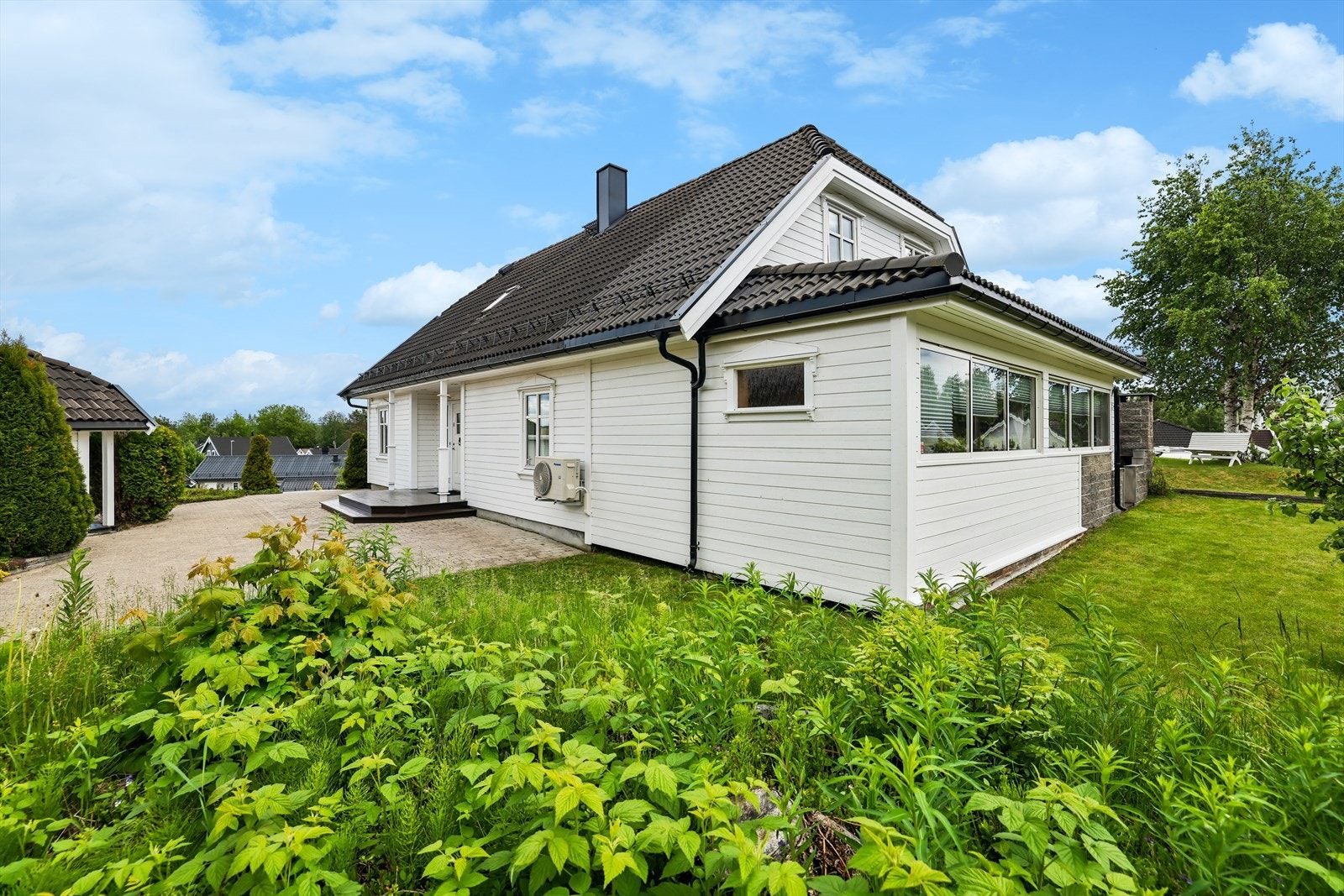 Fasade mot hage med plen, beplantning og skjermede oppholdssoner. Galleribilde