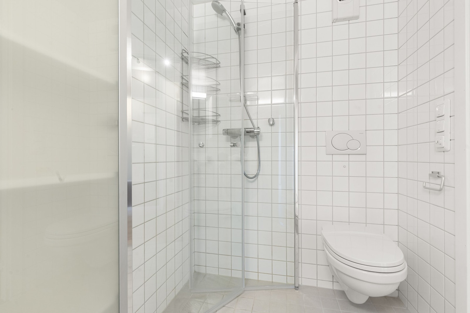 Badet har dusjsone med glassvegg og vegghengt wc, med flislagte overflater og et lyst og delikat uttrykk. Galleribilde