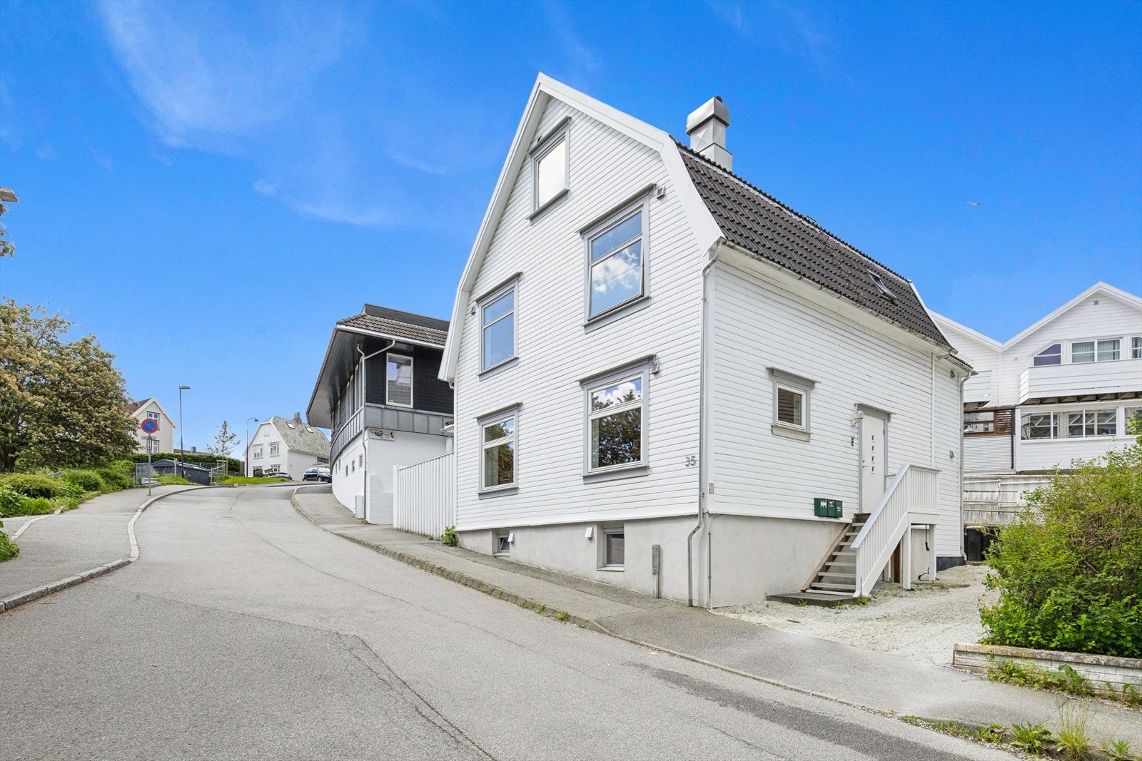 Leiligheten ligger fint til i en slak oppoverbakke, med utsyn mot grønne trær Galleribilde