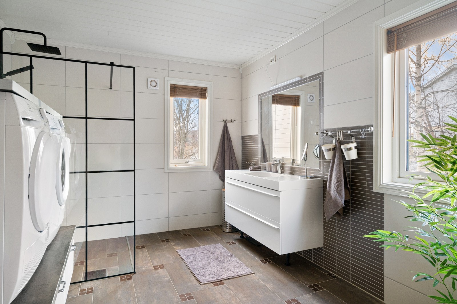 Stort bad med dusjhjørne og plass for vaskemaskin.