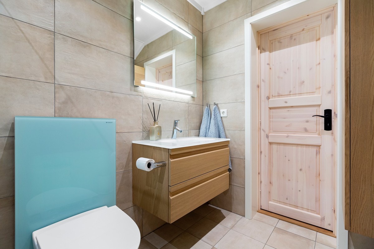 Badet er innredet med moderne fliser på gulv og vegg, og malte plater i himling. Galleribilde