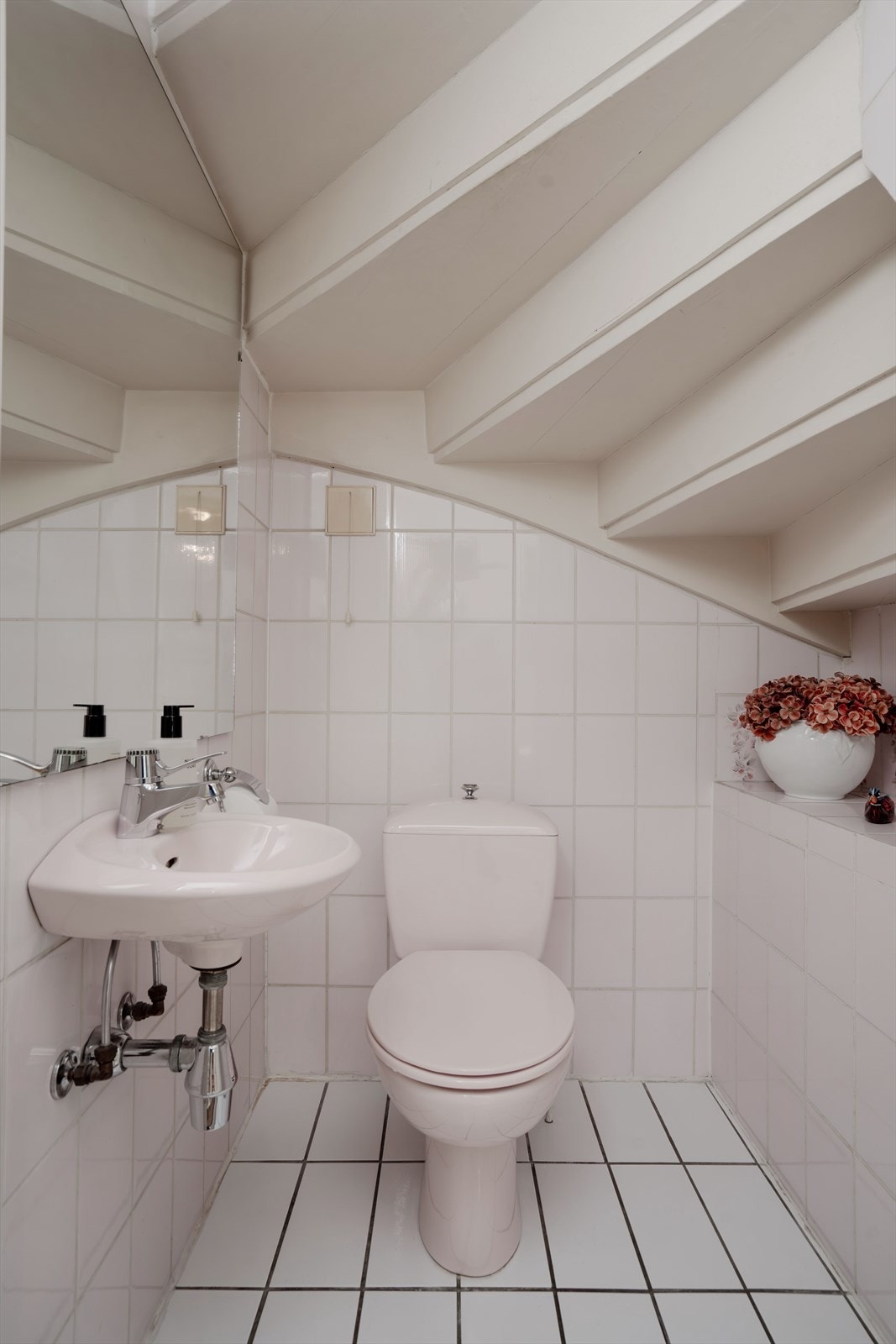 Praktisk toalettrom i 1. etasje, plassert under trappen. Rommet har fliser på gulv og vegger, samt gulvvarme. Galleribilde