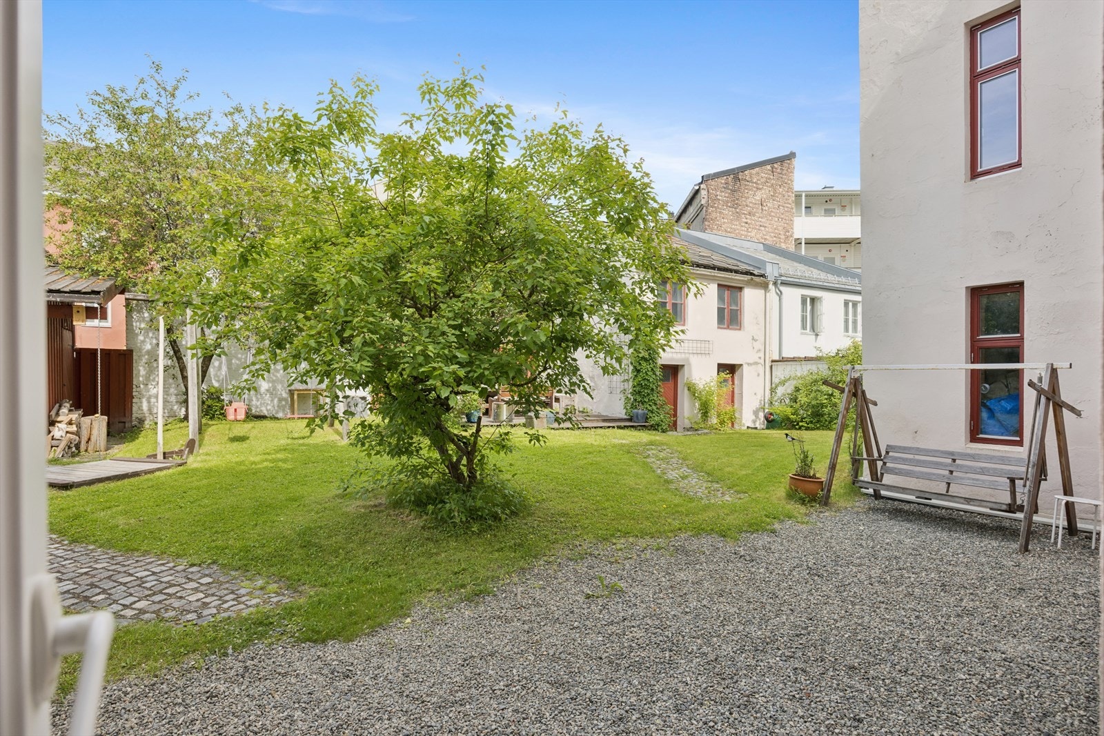 Solfylt bakgård med blant annet platting, utemøbler, grill og båltønne. Galleribilde