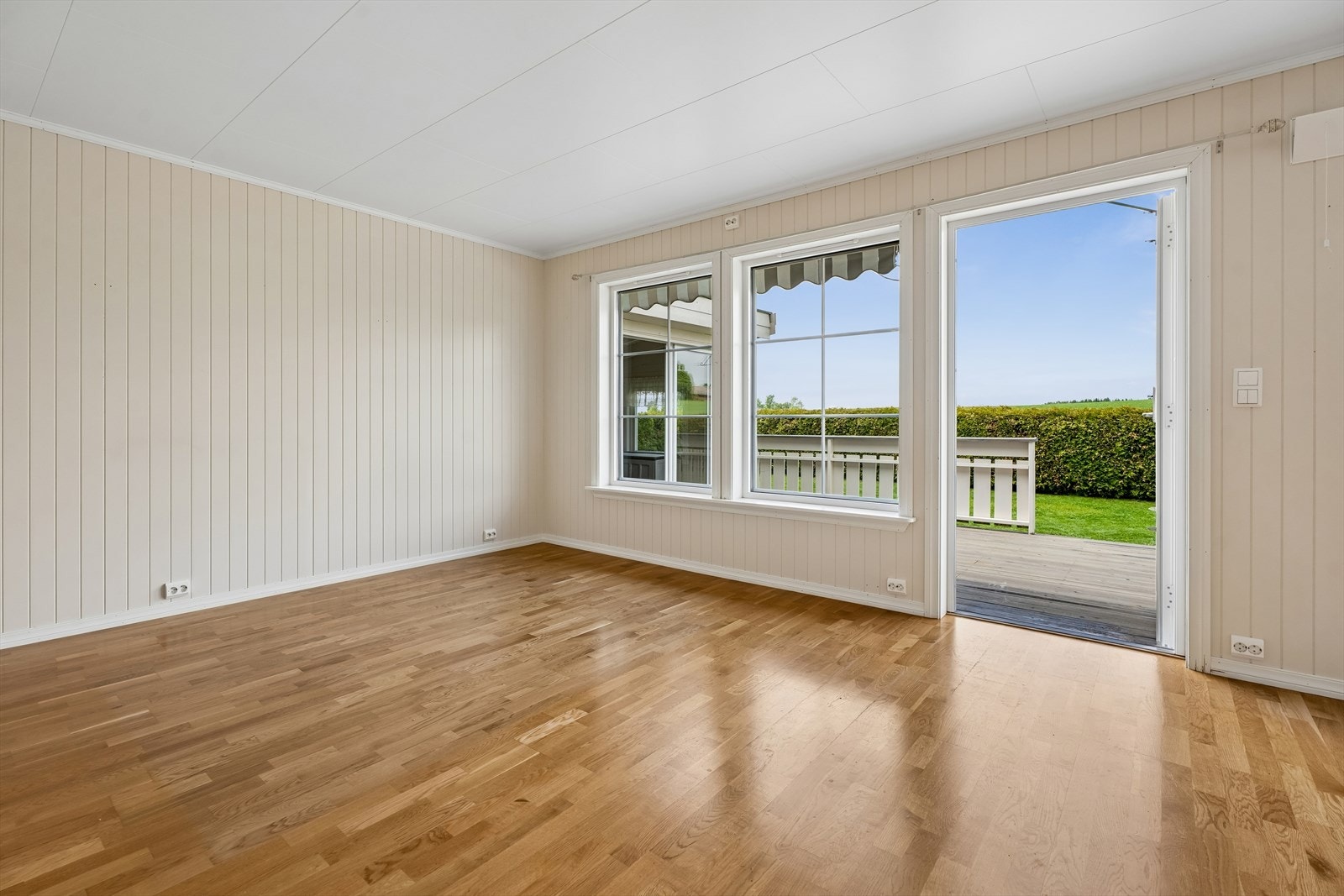 Terrassedøren i malt tre åpner opp for en sømløs overgang til uteområdet. Galleribilde