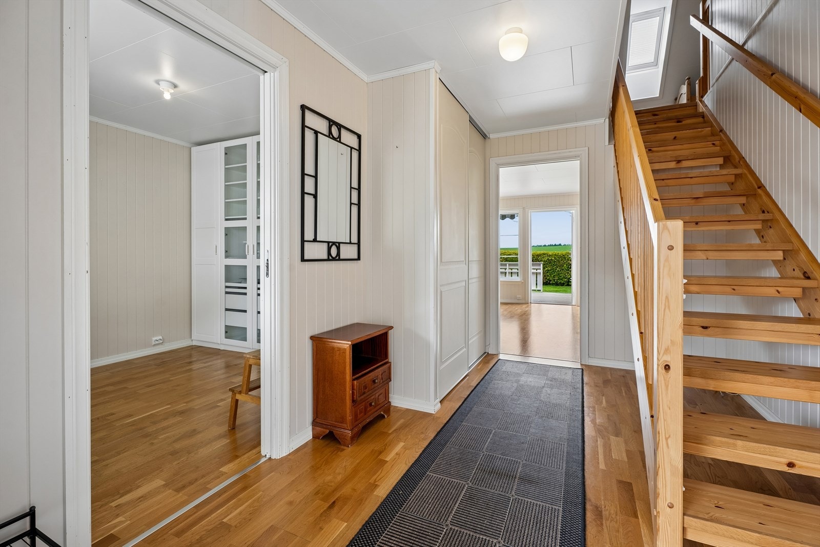 Fra gangen er det tilgang til soverom, bad og stue. Den lakkerte tretrappen fører opp til andre etasje. Galleribilde
