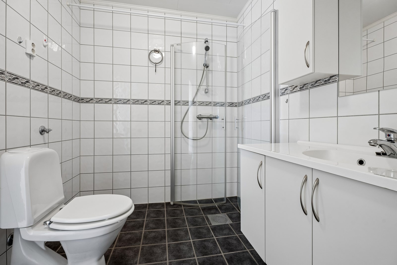Badet er utstyrt med dusjhjørne, toalett, servant med innredning og har opplegg for vaskemaskin. Galleribilde