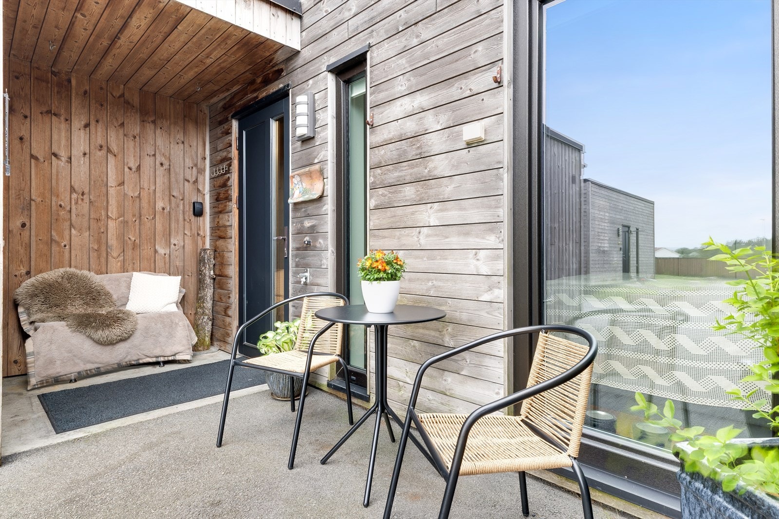 Overbygget inngangsparti med plass til en liten sittegruppe. Galleribilde