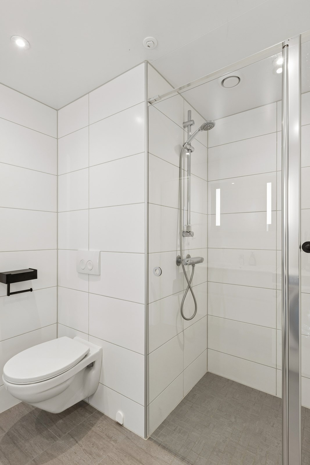 Badet er utstyrt med vegghengt klosett og dusjhjørne med glassdører. Galleribilde