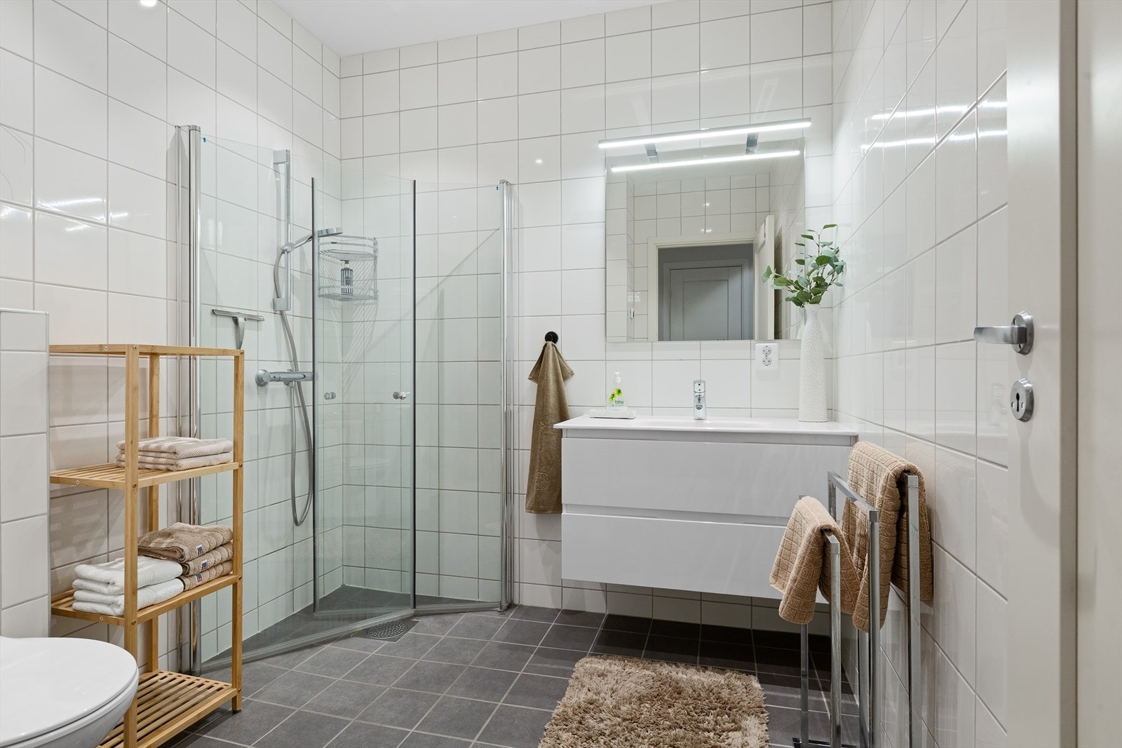 Badet i første etasje har fliser på gulv og vegger, gulvvarme og dusj med glassdører. Galleribilde