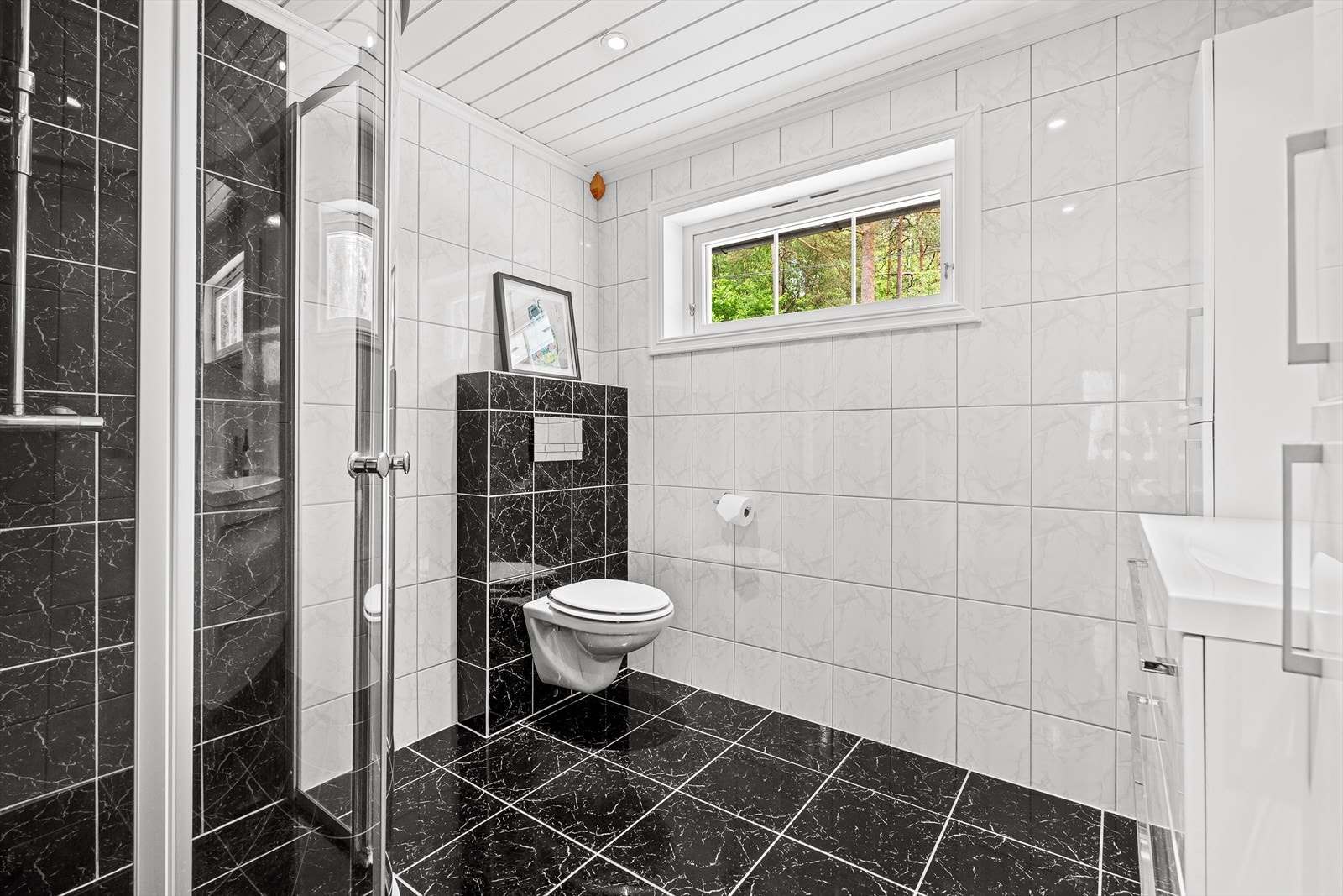 Badet fra 2010 har flislagte overflater, vegghengt toalett og dusjhjørne med dører i herdet glass. Galleribilde