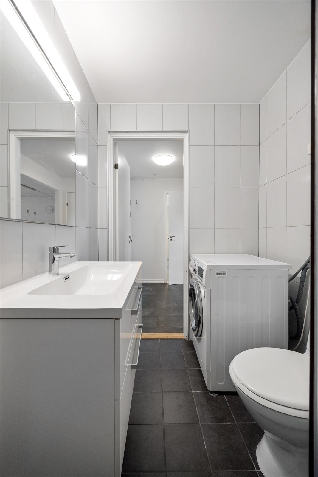 Badet er innredet med dusjhjørne, servant med innredning, speil, toalett samt opplegg for vaskemaskin. Galleribilde