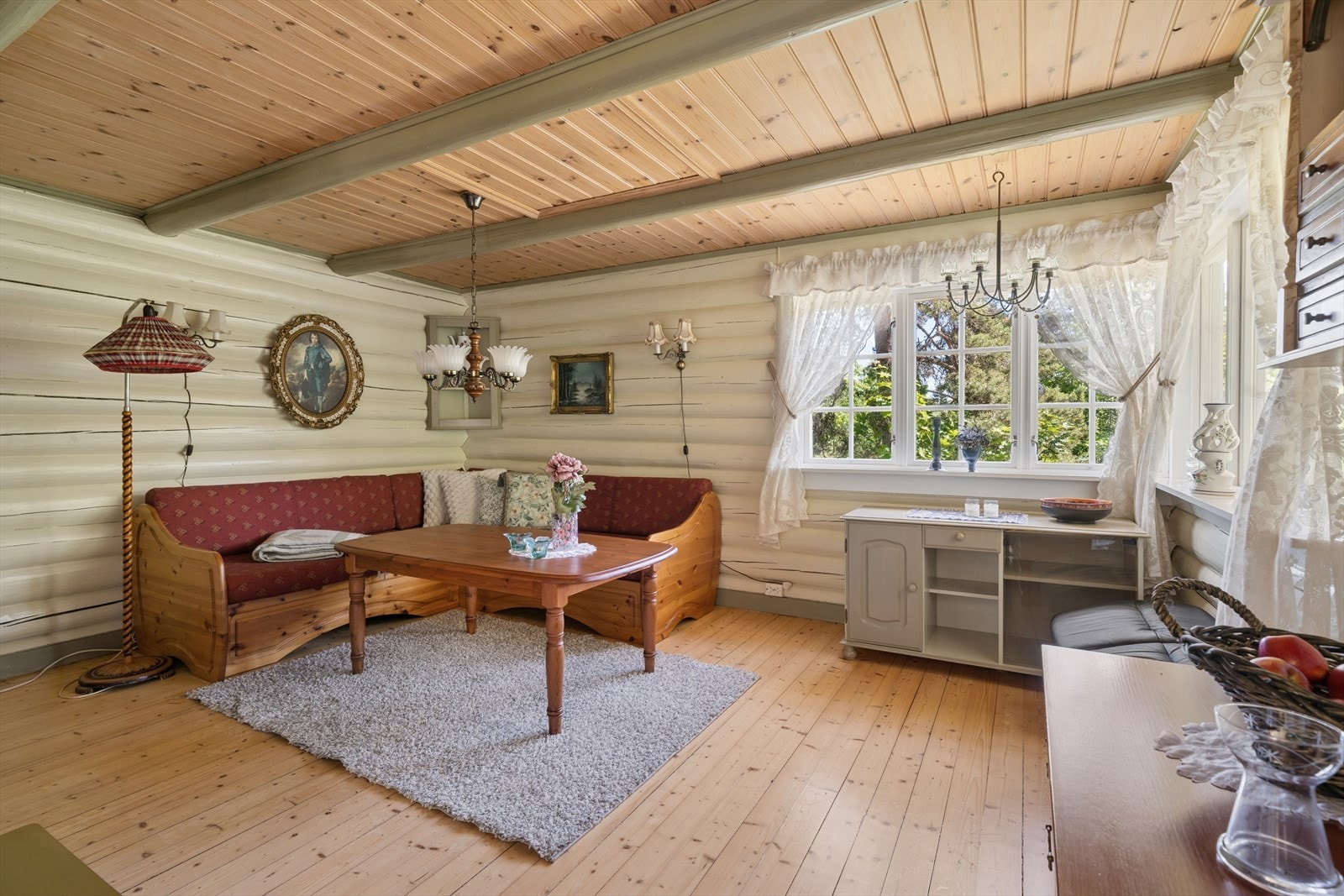 Stuen er et naturlig samlingspunkt med synlige tømmervegger og panel i taket. Galleribilde