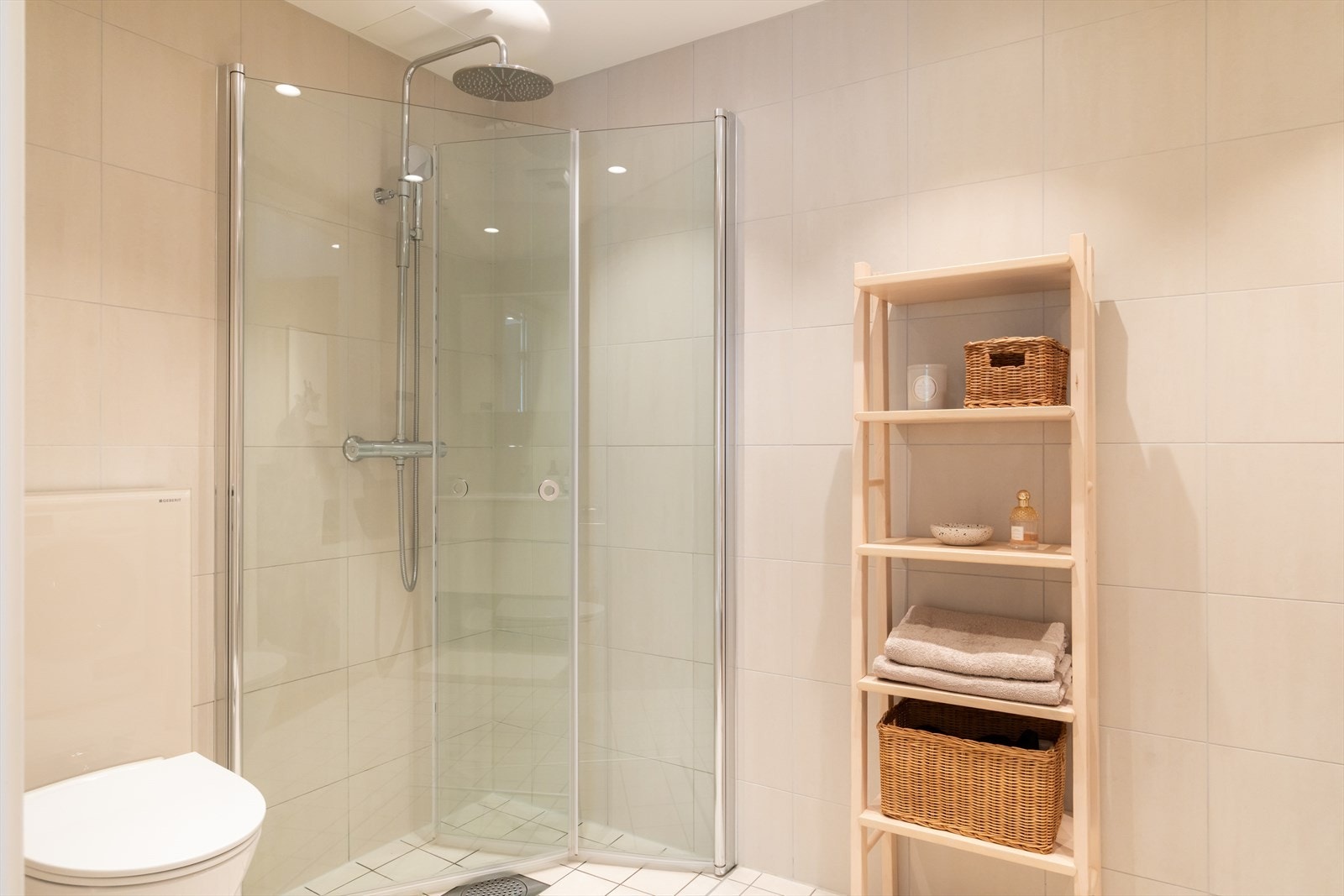 Badet er innredet med vegghengt klosett, servant med innredning, speilskap med lys og dusjhjørne med svingbare glassdører. Galleribilde