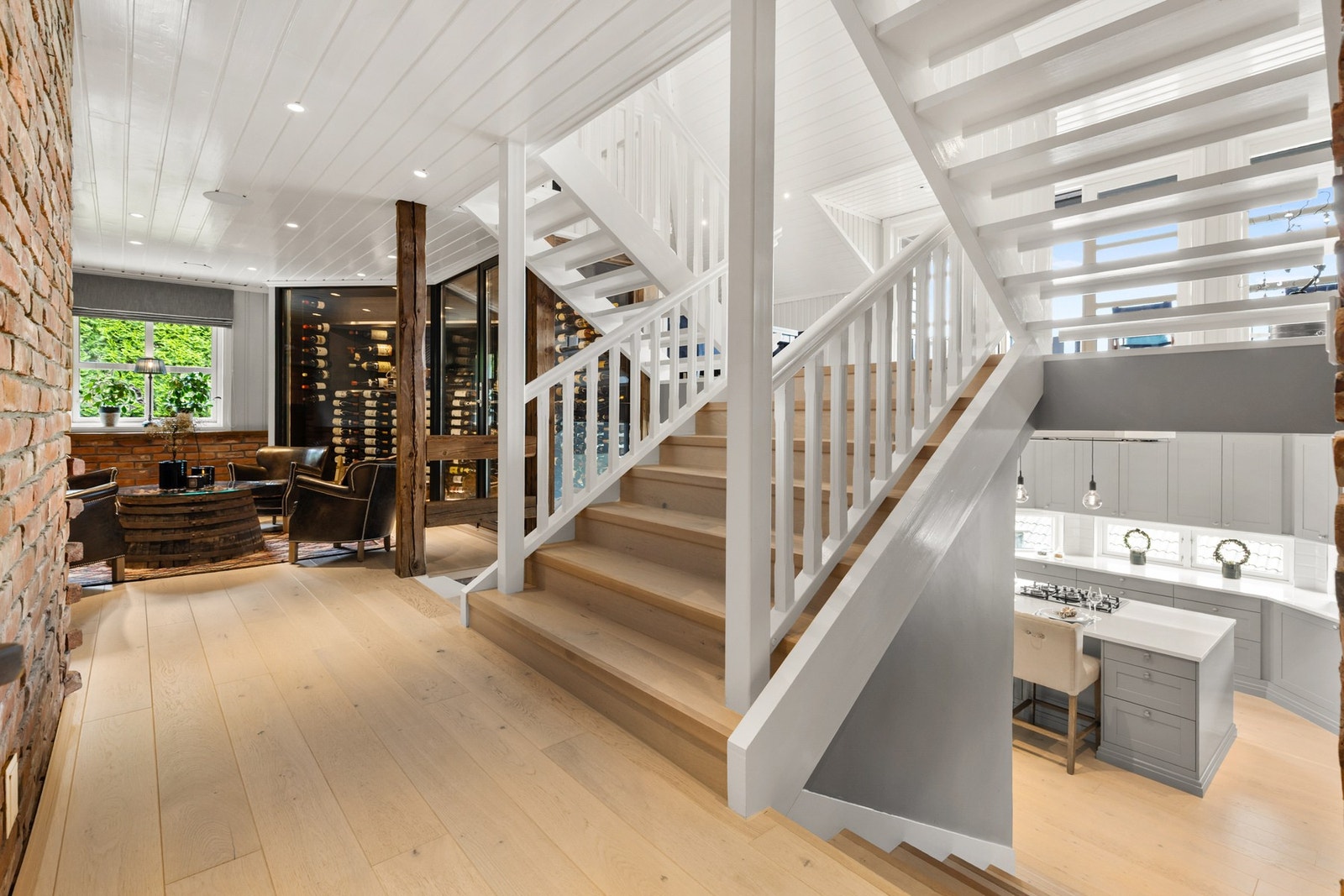 Lun og stilig stue med eikeparkett på gulv, panel på vegger og downlights i himling Galleribilde