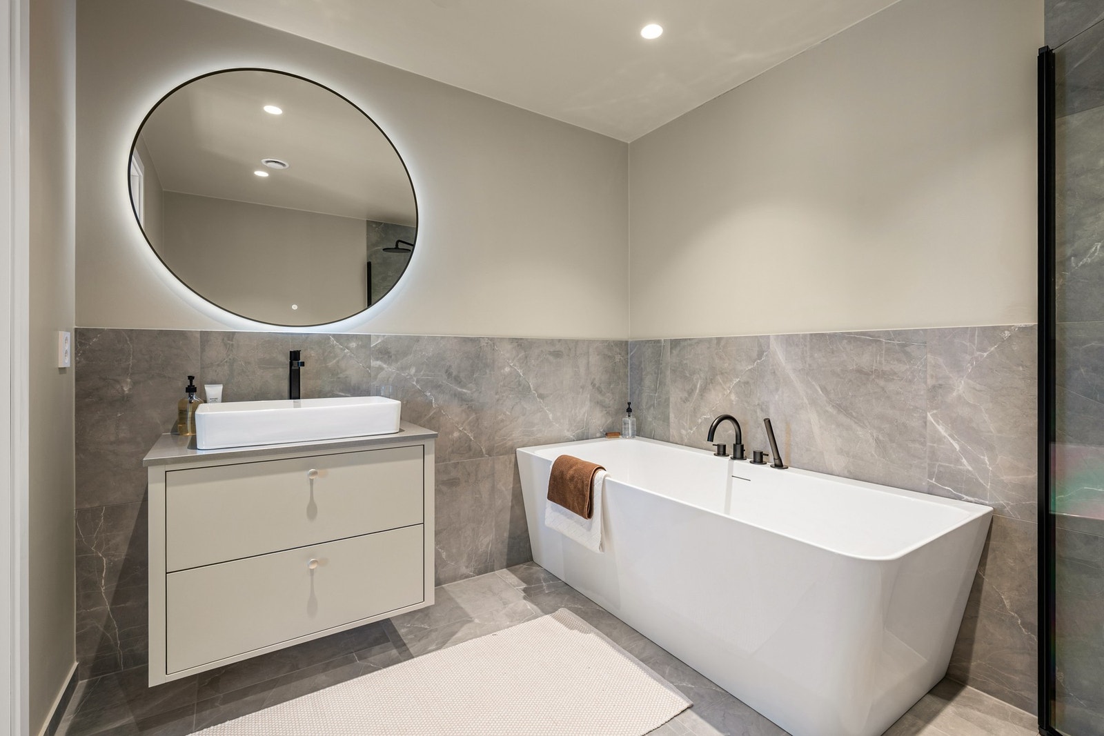 Badet er romslig og smakfullt innredet med servantinnredning, belyst speil, vegghengt toalett, badekar og separat dusjsone. Galleribilde