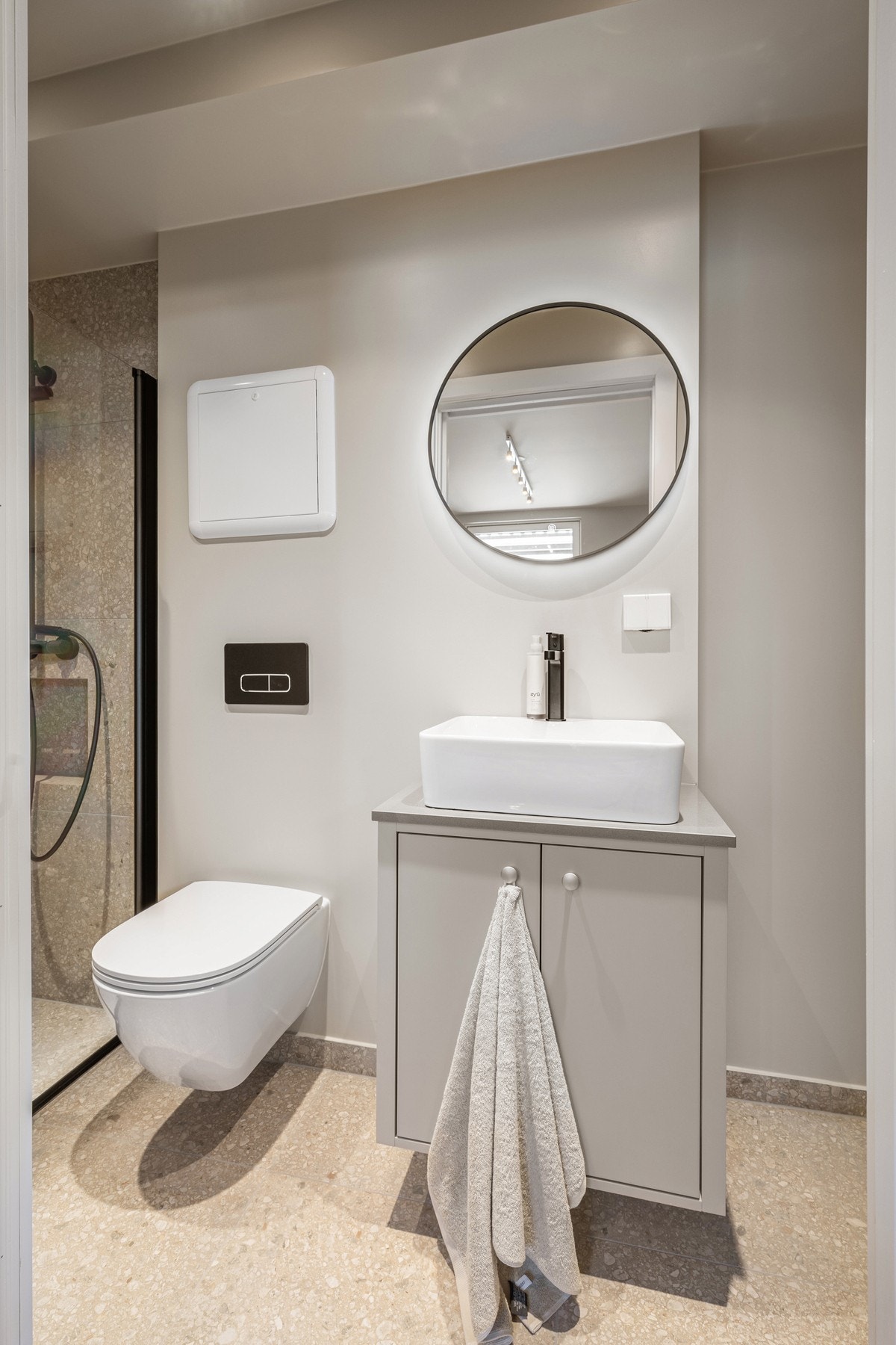Badet i underetasjen har et moderne uttrykk med flislagte overflater, servantinnredning, vegghengt toalett og dusjsone med sorte detaljer. Galleribilde