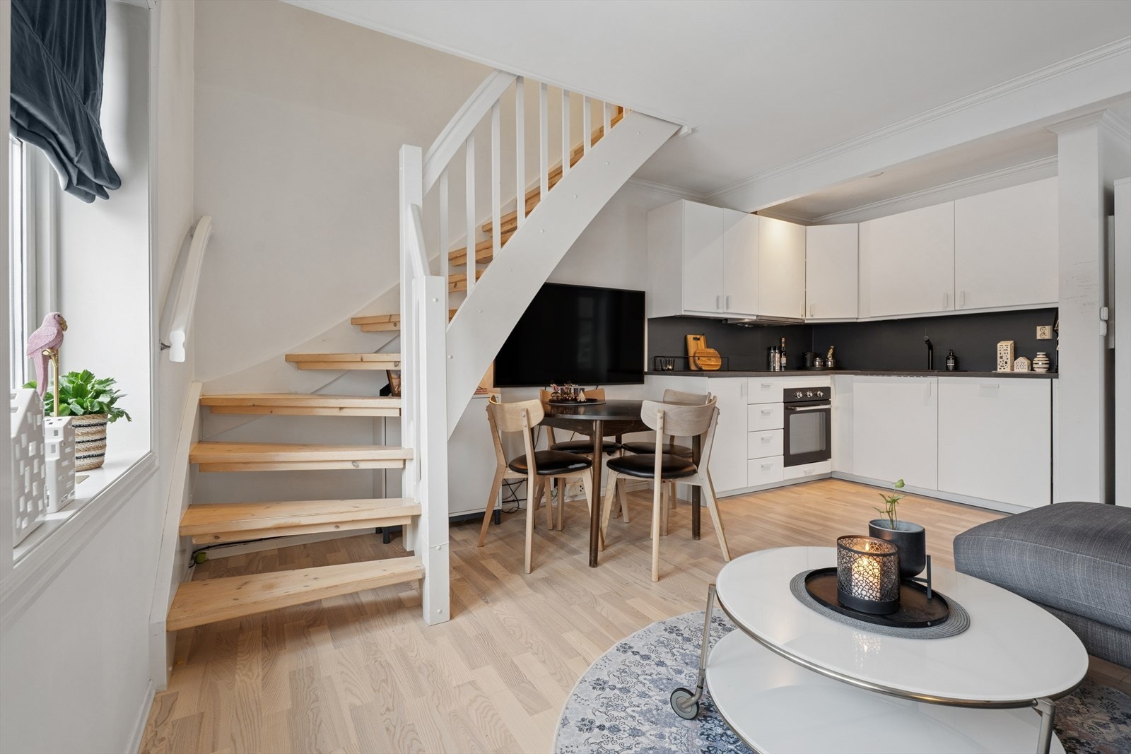 Den åpne tretrappen med hvitmalt rekkverk leder opp til loftsetasjen. Galleribilde