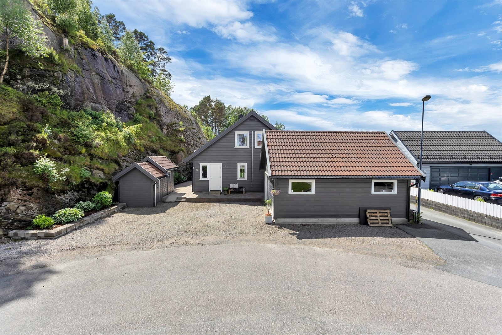 Gruset innkjørsel og gårdsplass med god plass til parkering. I tillegg til garasjen er det en frittliggende bod på tomten. Galleribilde